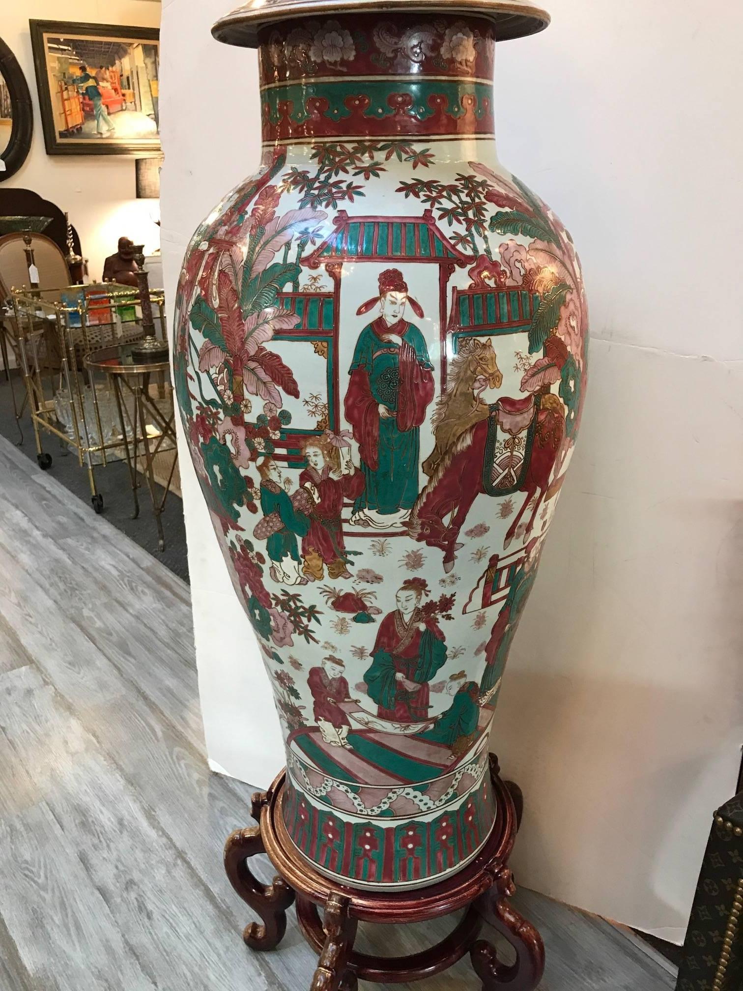A large hand-painted Chinese porcelain palace vase on Stand. The off-white background with hand-painted Chinese scenes of people and gardens. The colors pallet is in iron red and jade green. The lave vase comes with the wood base. The height of the