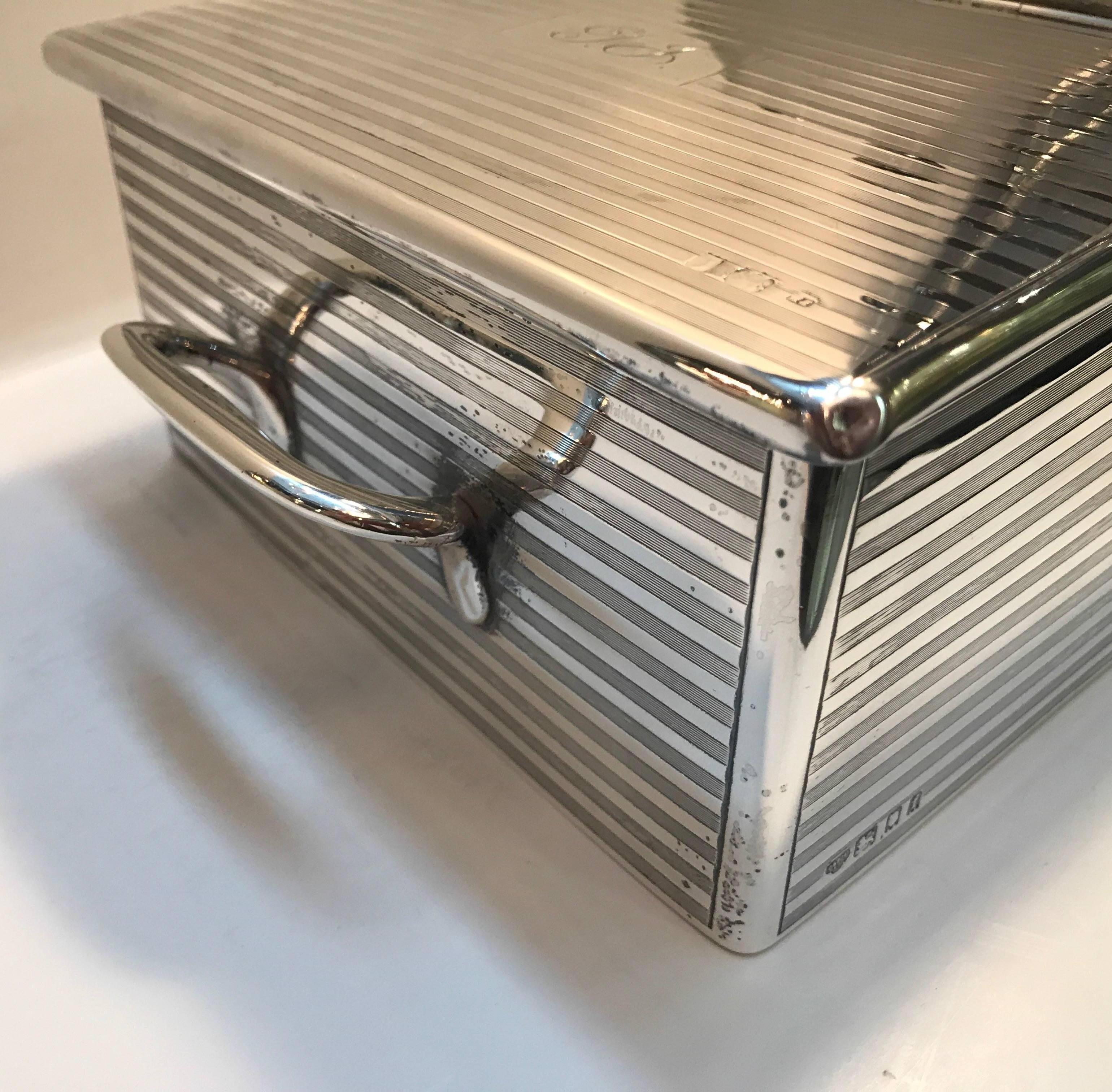 Sterling silver cigar box made by Goldsmiths and Silversmiths Company, Regent Street, London, 1921. The ribbed case with two carrying handles, extensively hallmarked all-over. The two hinged lids opening to a cedar lined interior, both flanking a