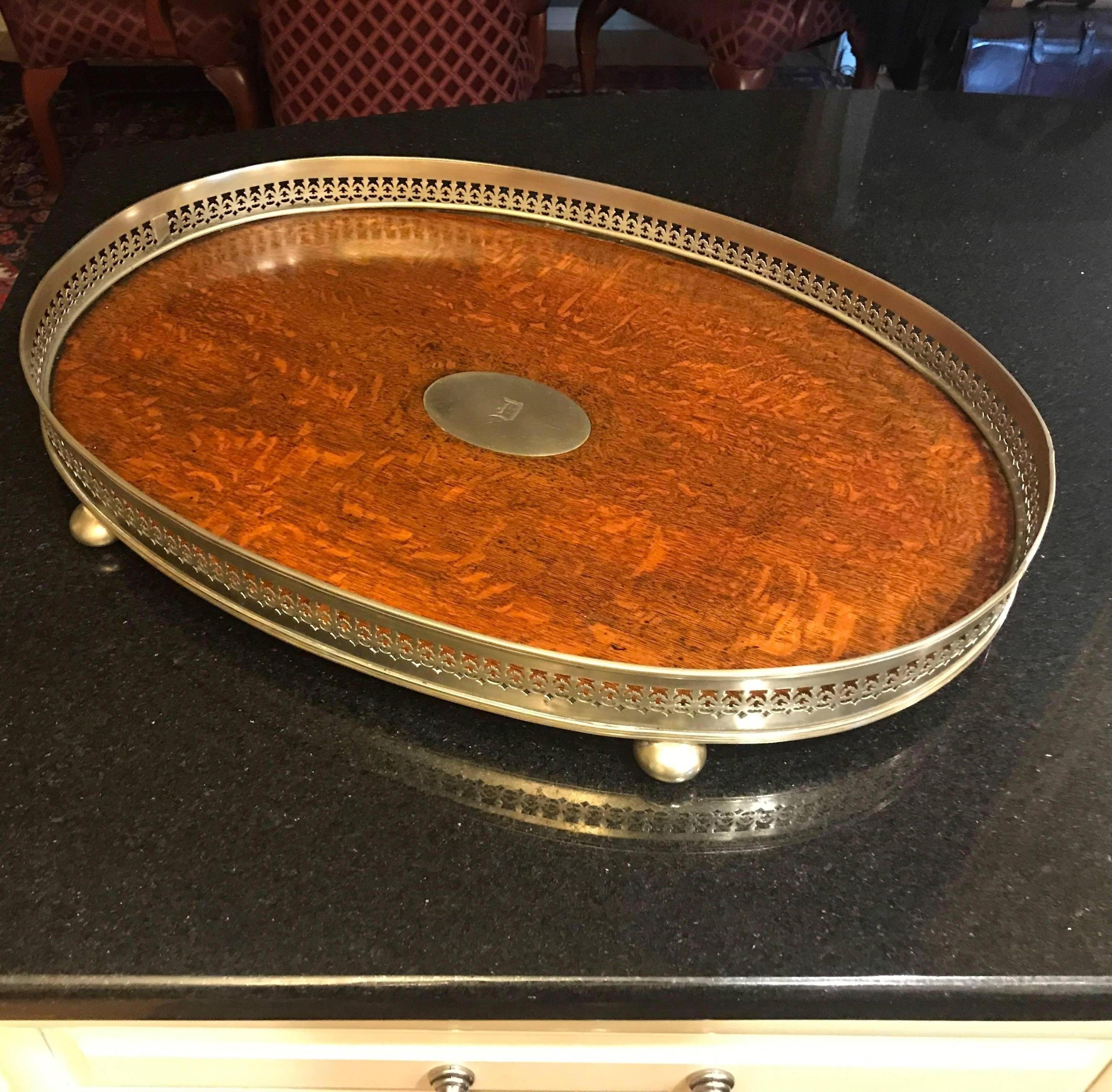 An English oak and brass gallery tray with center plaque. The pierced edge with bun feet with solid oak surface. The central solid brass plaque with an engrave D.
