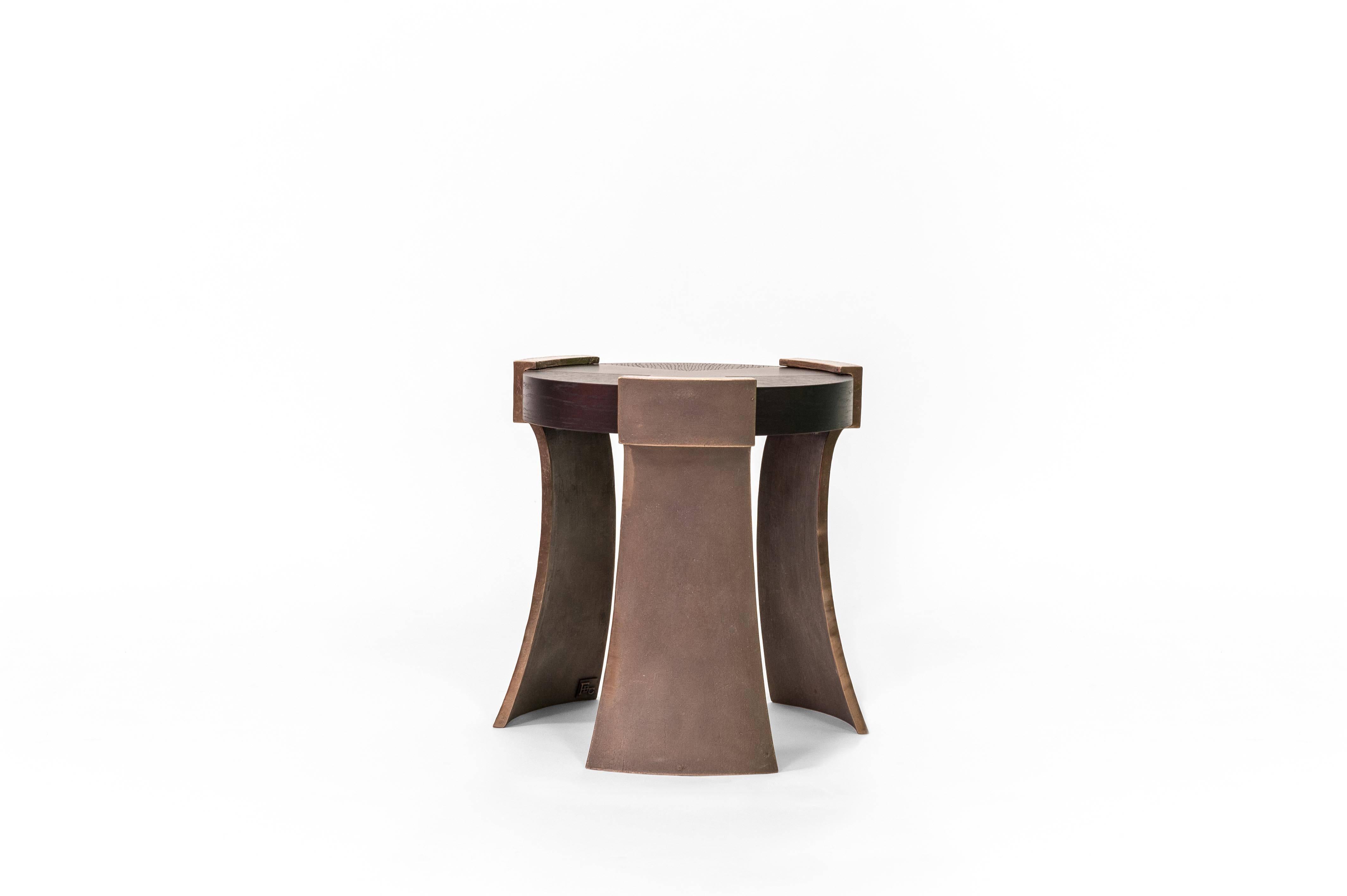 The Oswald side table shows reflection to a Roman shield. The contrast of the rough curved bronze legs compliment the strong geometric lines within the top.
  