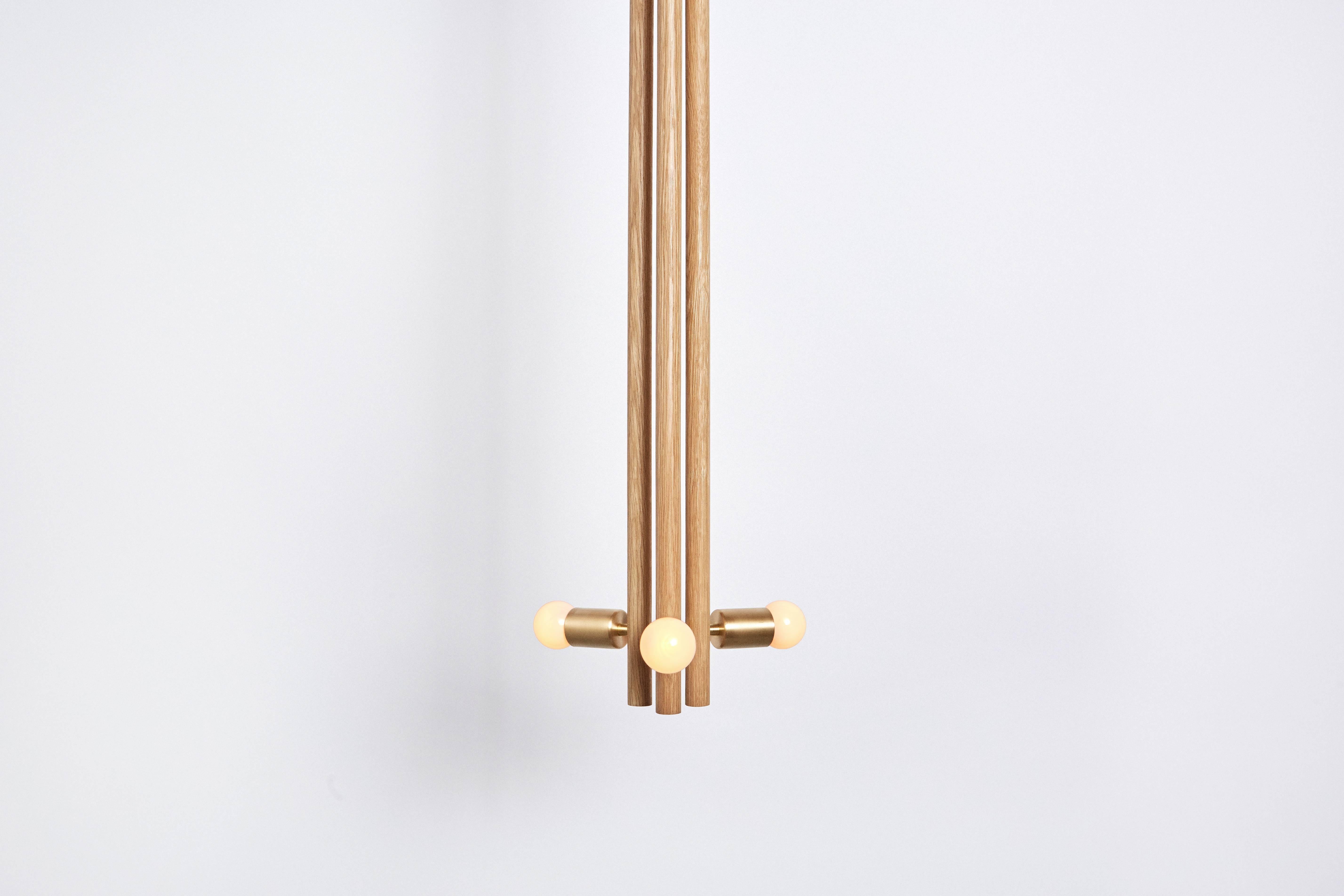 The Lodge pendant is a singular wooden column, composed of three turned wooden forms. Held together by a network of metal tubing, with a milled metal ball connection, the bulbs radiate about the column. 

Available in natural oak/hewn brass and
