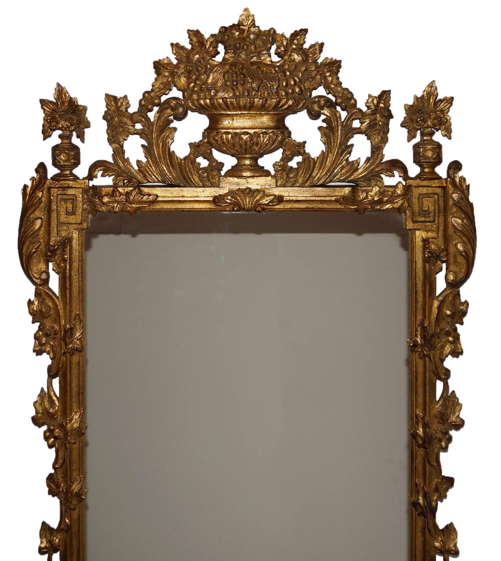 Highly ornamented Italian giltwood mirror having beautifully carved details throughout. Mirror is surmounted by an exuberant urn form crest with foliate and grape motifs. Foliate motifs continue throughout with acanthus leaves and grapevines