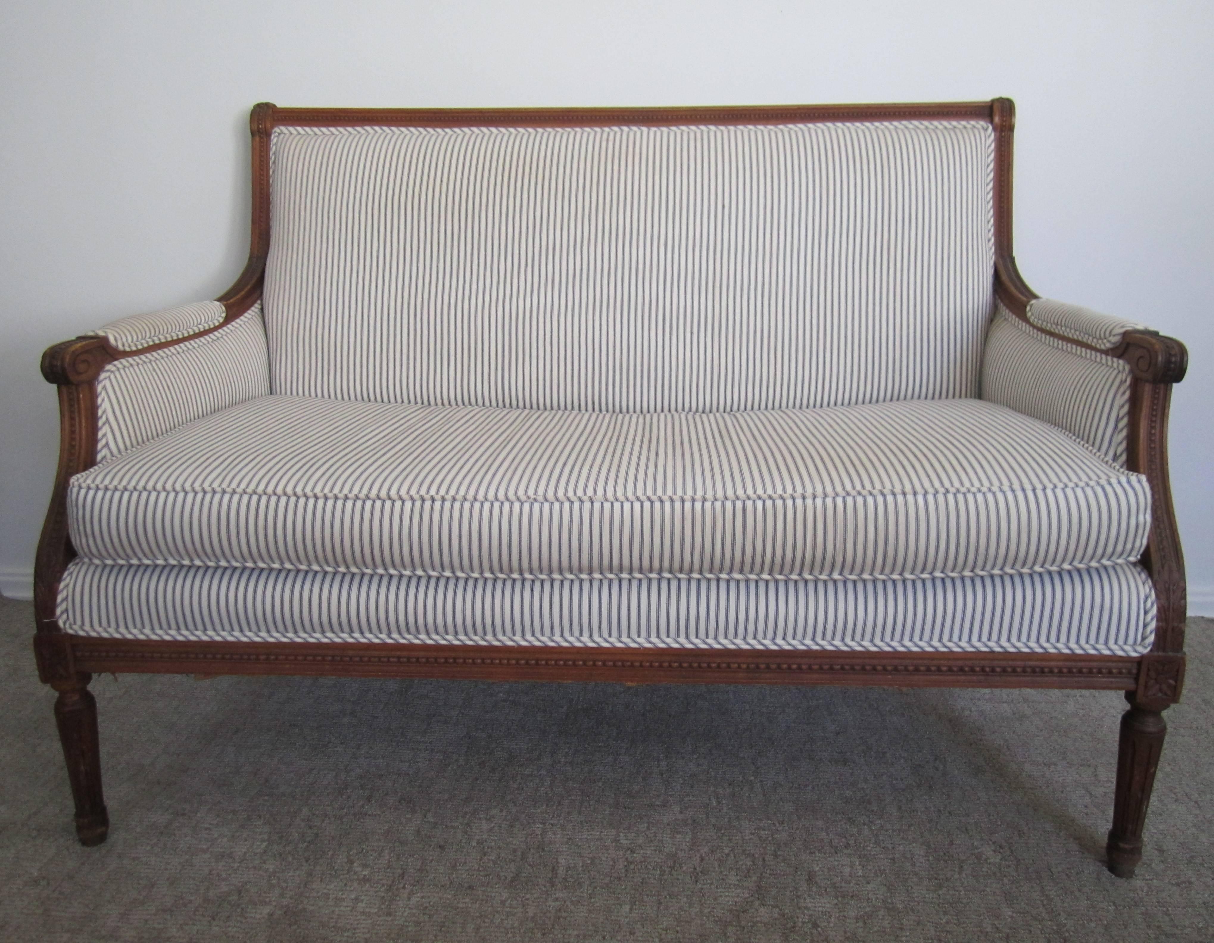 A beautiful antique French Louis XVI style settee sofa upholstered, front, back and sides, in a blue and white ticking fabric. Solid wood frame. Measurements include: 46