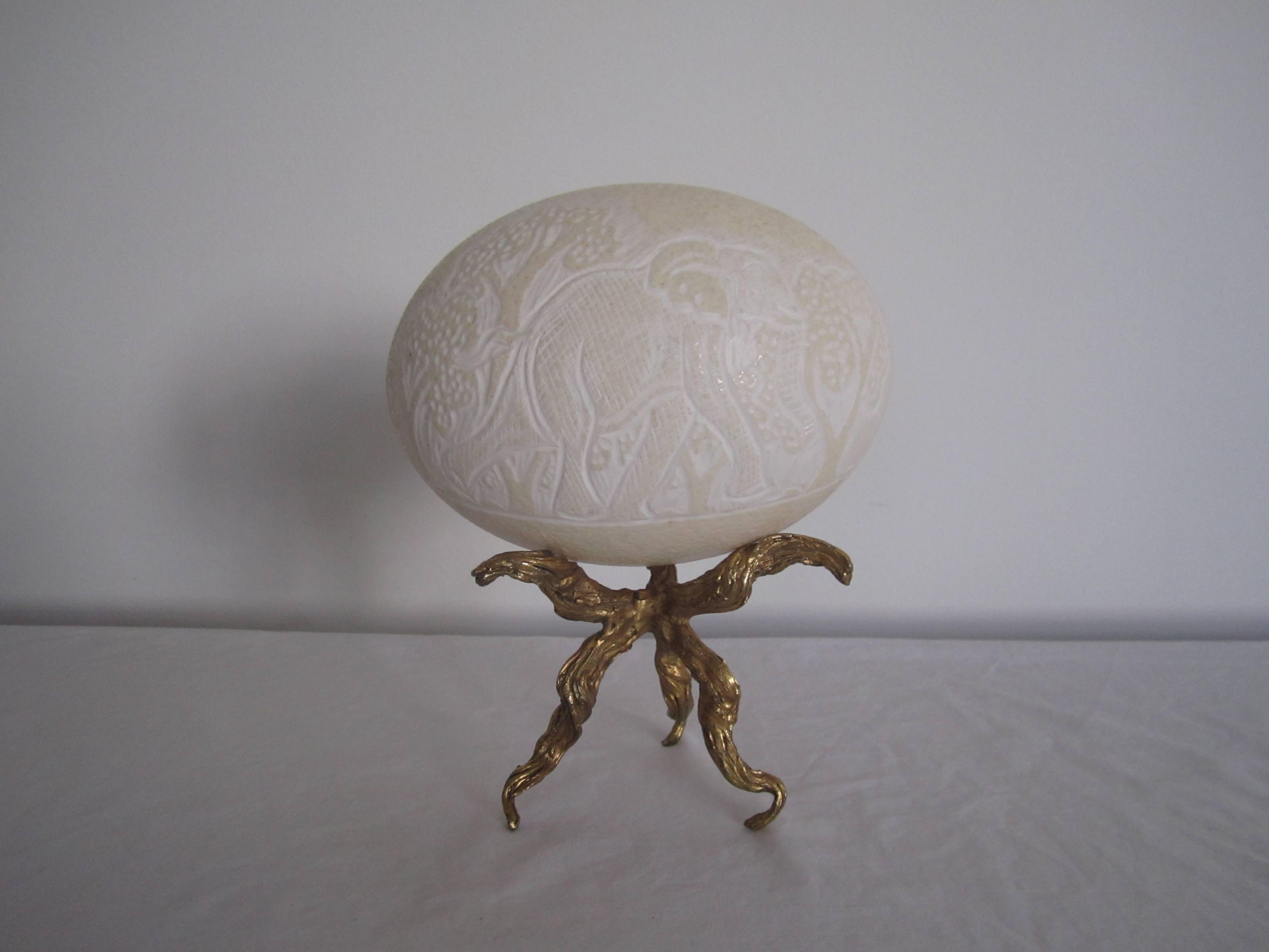 A carved ostrich egg; carved with an elephant on one side and a rhino on the other, sitting on a twisted metal gold base. Item available here online and by request, can be made available at my showcase space in the Showplace Antique + Design Center,
