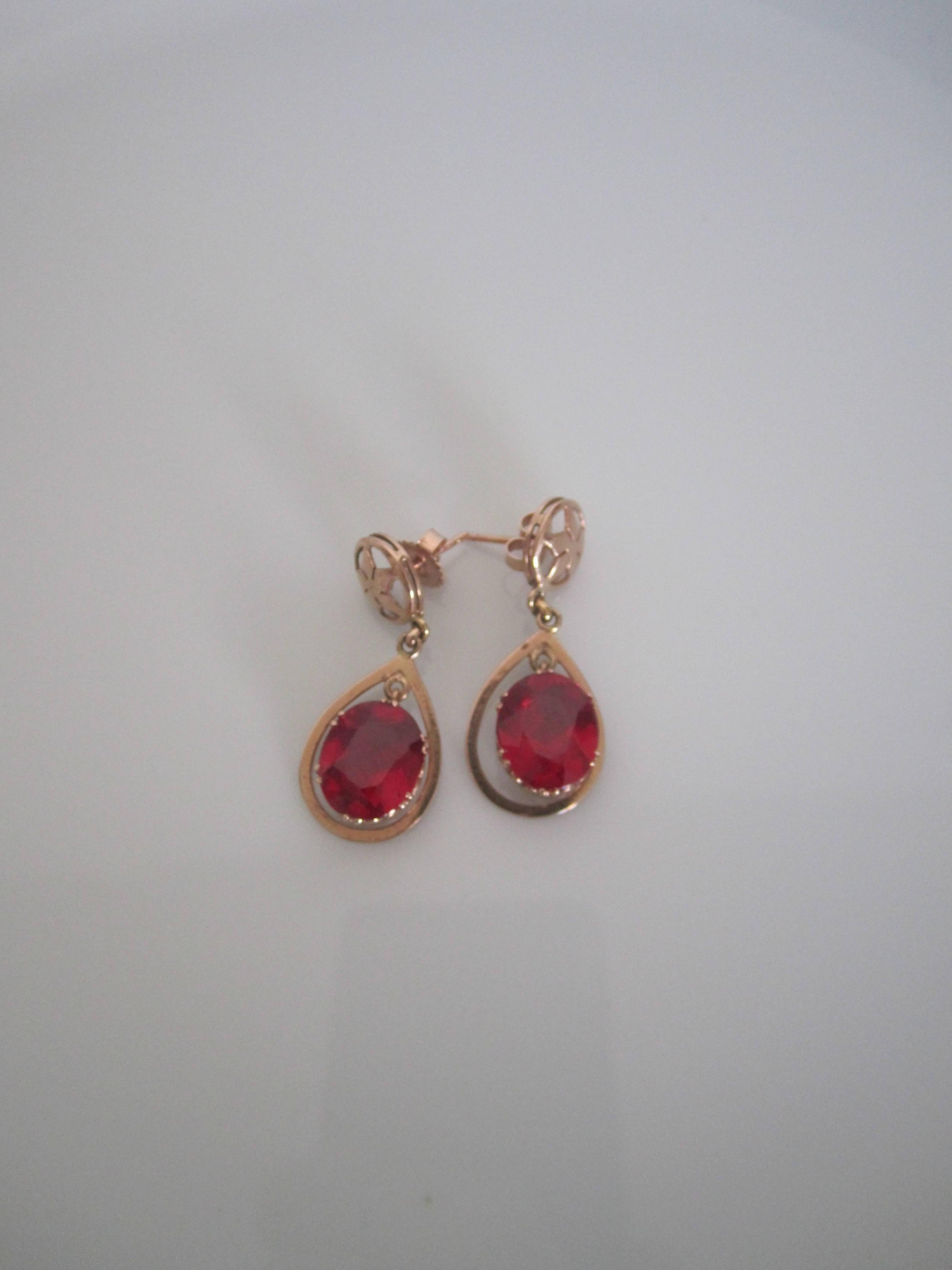 A beautiful pair of vintage 14-karat pink or rose gold earrings with large red ruby-like stones, circa early to mid-20th century. Stones are set in a detailed 14-karat pink or rose gold setting. Backs have been newly adjusted to accommodate pierced