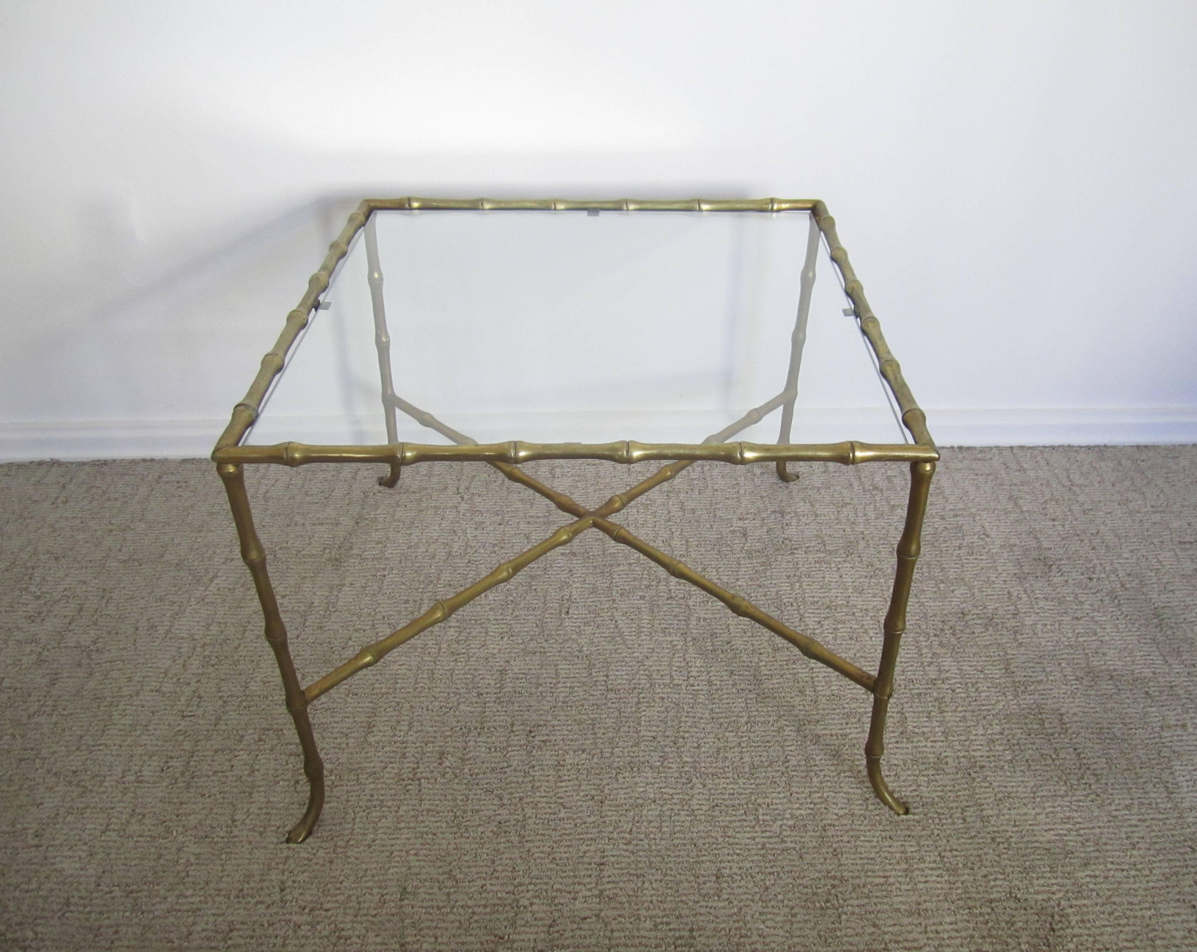 A substantial brass and glass end or side table with 'bamboo' frame, attributed to design house Maison Baguès, France, circa mid-20th century. Frame is solid brass. Table has an 'X' stretcher base and brass screw hardware, finished with an inset