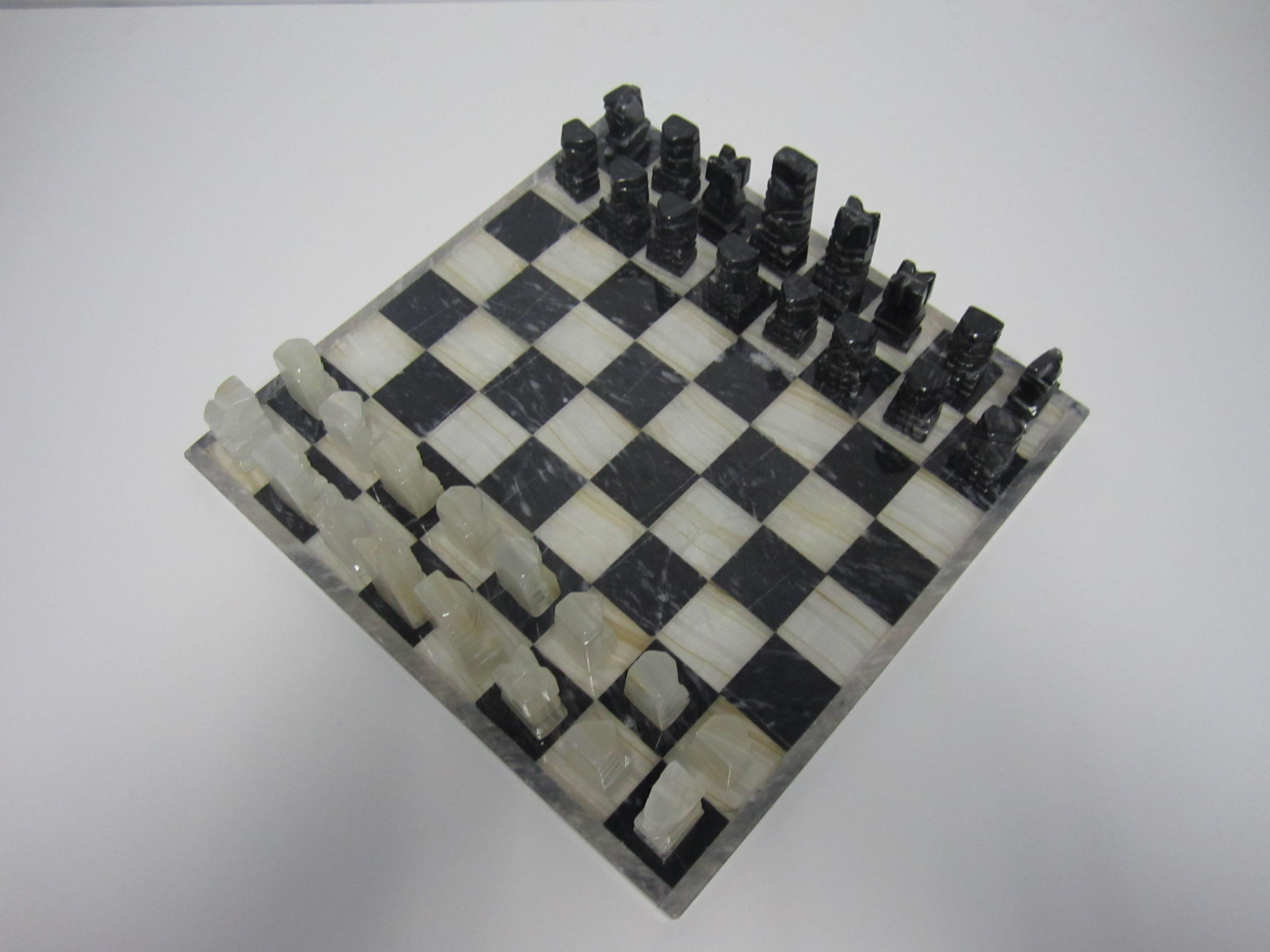 A vintage modern black and white marble and onyx chess set. Complete set of 32 pieces plus board. Board is black and white with grey boarder. Pieces are hand-carved black and 'white' onyx (white onyx hue ranges from white to off-white.) Circa 1970s.