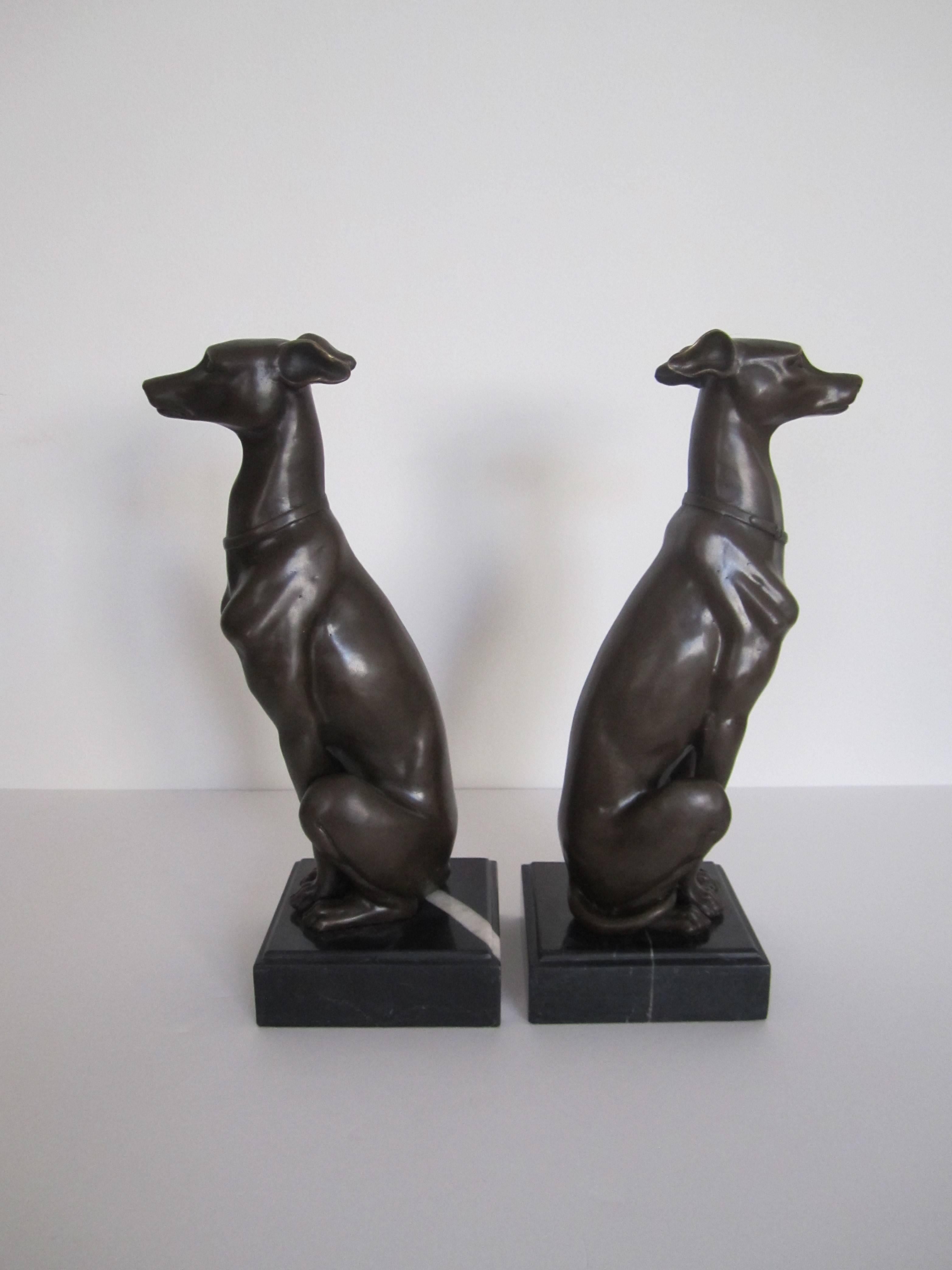 A beautiful and substantial paired of Art Deco bronze whippet or greyhound dog sculpture bookends, seated on black and white marble bases, measuring 11