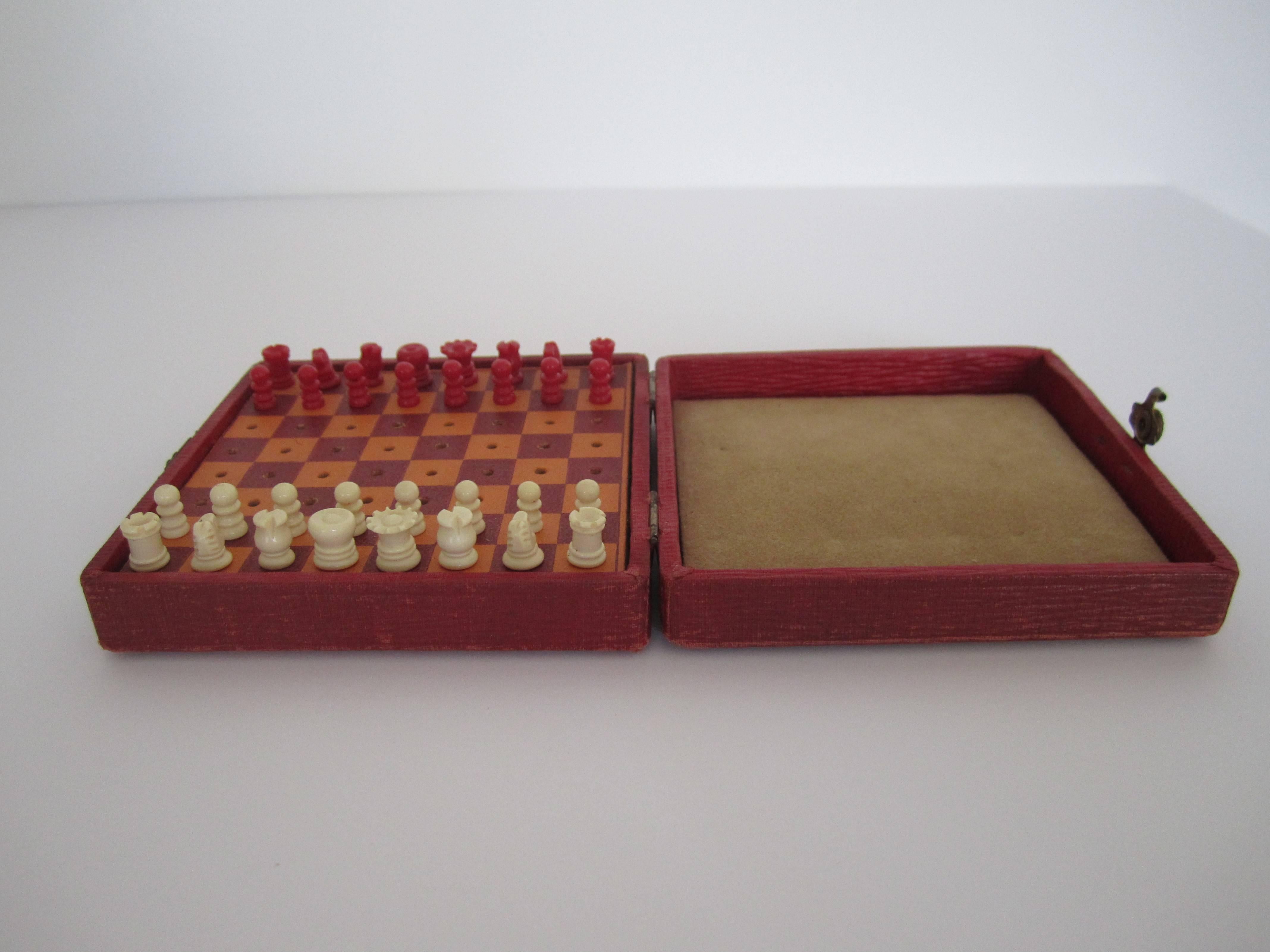A mini travel chess game set with red and cream (white) pieces all beautifully carved and solid. Box has clasp that snaps closed comfortably. Circa 1920s. 

Measurements closed: 4 in. x4 in. x 1.75 in.
Measurements open: 4 in. x 8 in. x .75