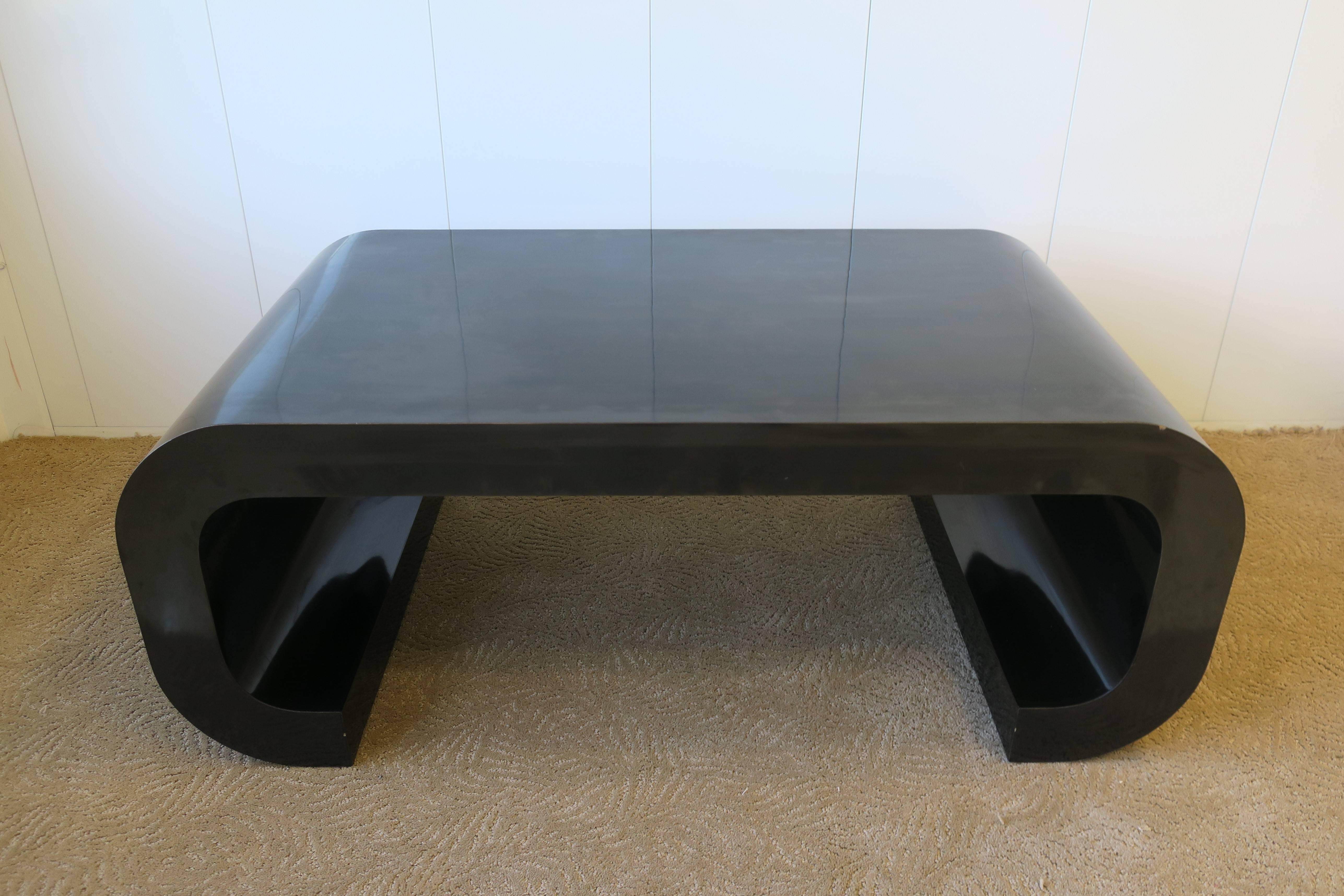 A chic '70s Modern scroll coffee or cocktail table in a black laminate veneer, in the style of designer Karl Springer, circa 1970s. 

Measurements: 42 in. W x 22 in D x 16 in. H. 

Table available here online. By request, table can be made available