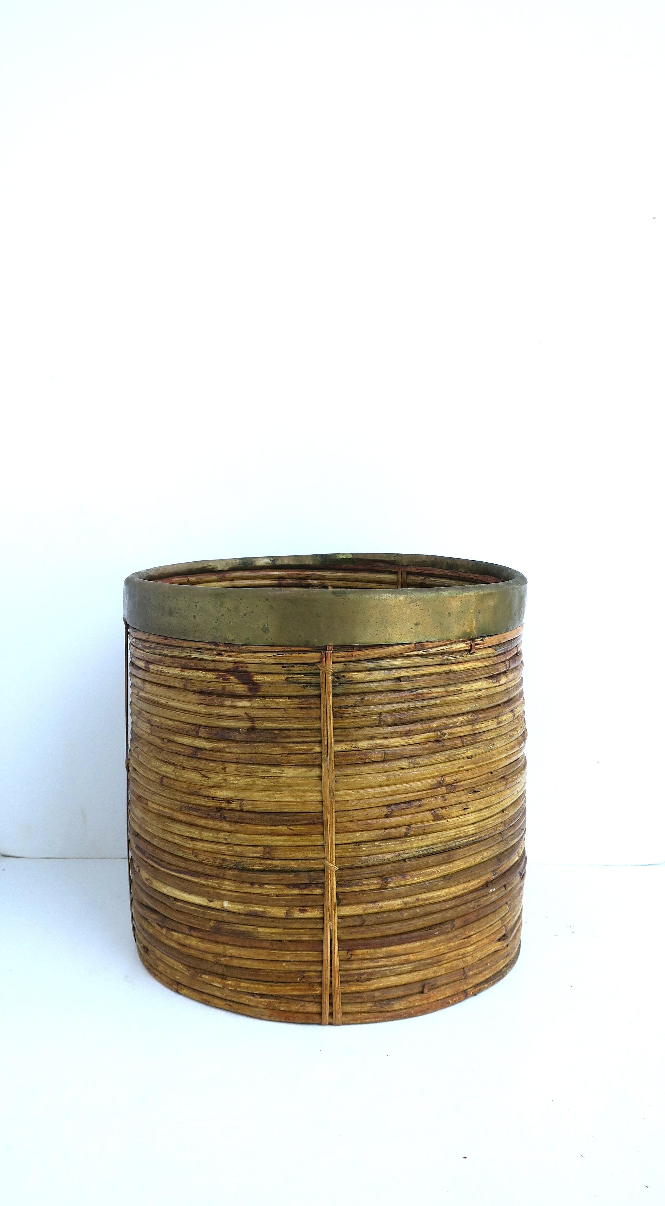 A coiled wicker and brass cachepot or wastebasket with brass rim, in the style of designer Gabrella Crespi, circa mid-20th century. Use as a plant potholder cachepot (demonstrated) or as a wastebasket trash can, etc. 