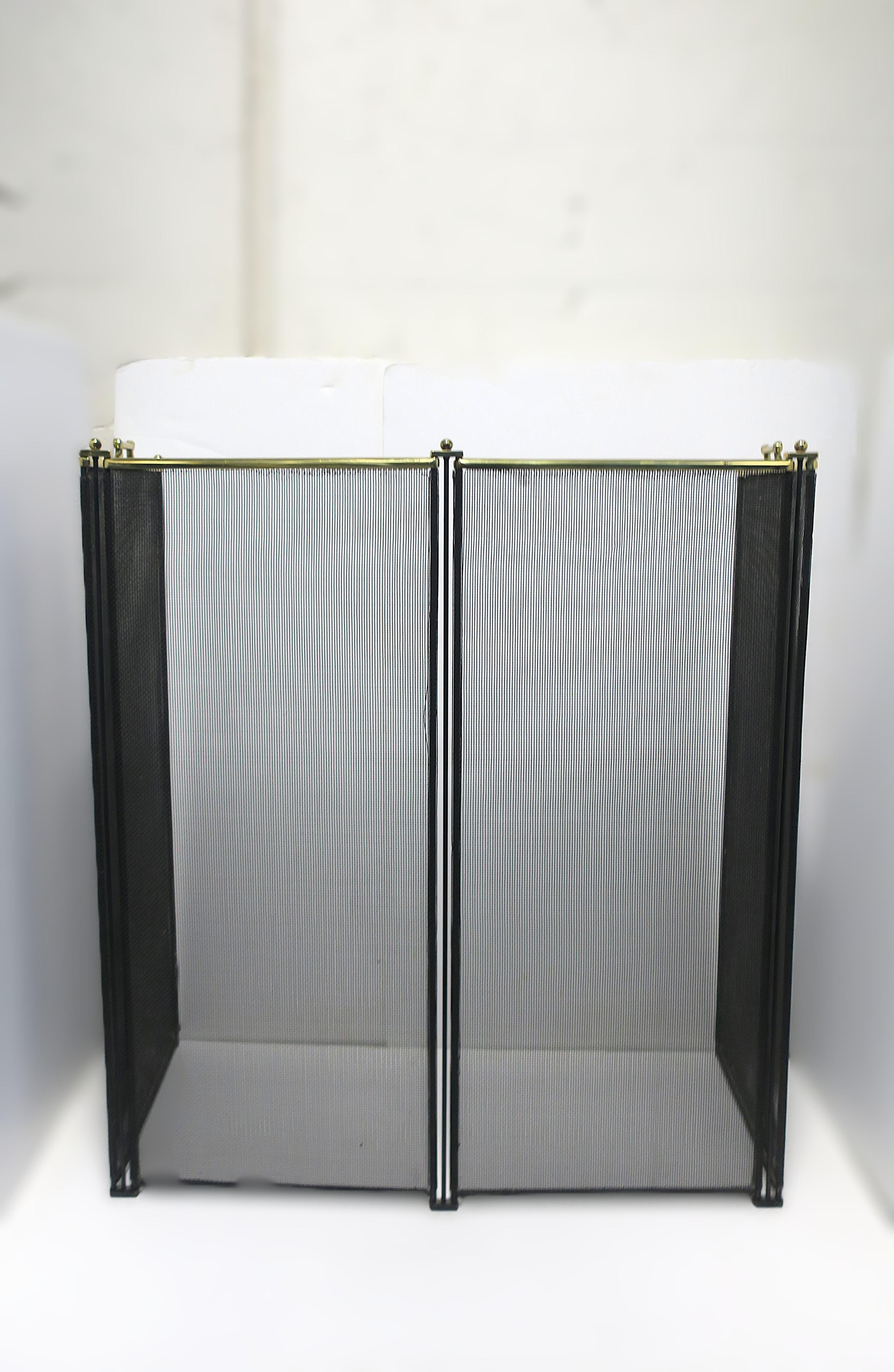 A well-made black mesh metal and brass fireplace screen. Screen is a black mesh metal with four (4) panels and brass detail along top edge; a brass bar with brass ball finials at each intersection/corner and two brass handles for easy lifting. Brass