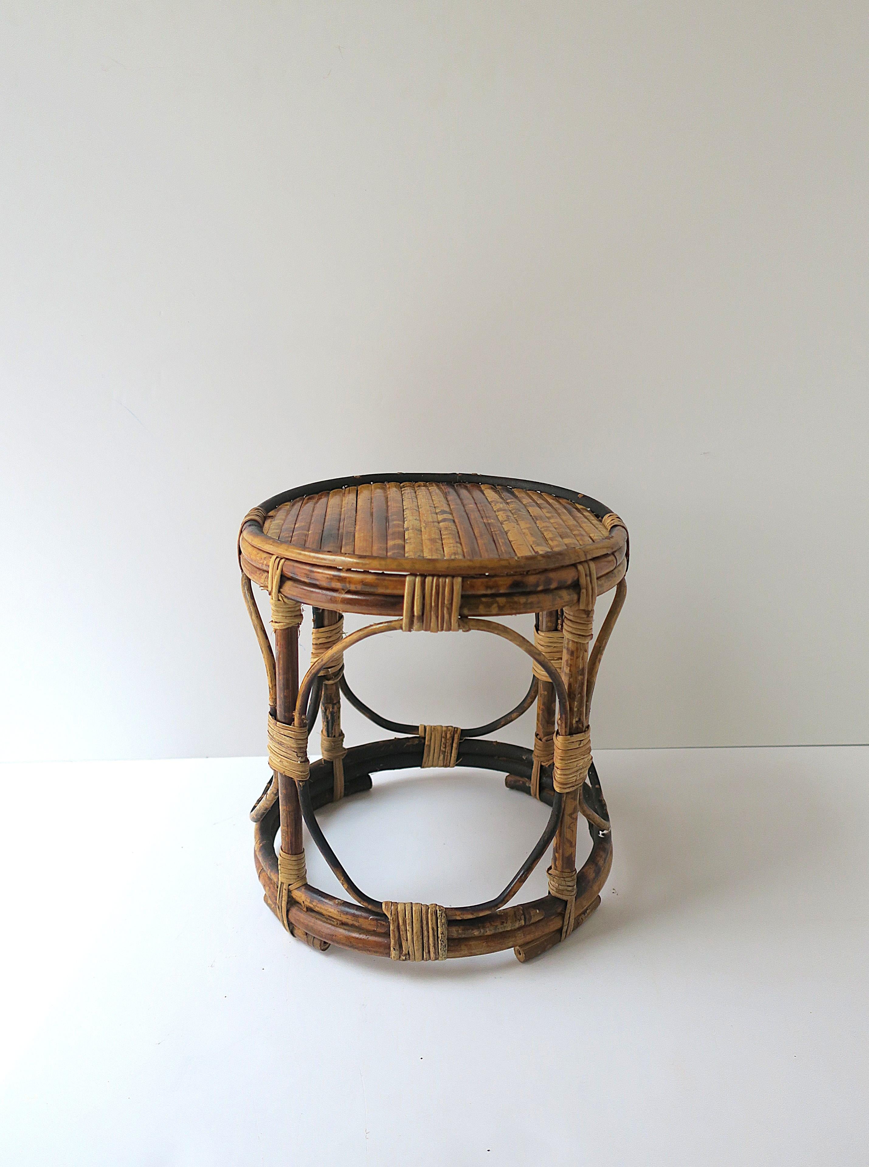 A small round bamboo and wicker wrapped table, circa mid-20th century. Use as a drinks table, plant stand, etc. Table is round, lightweight, bamboo with wicker wrapped joints. A convenient table for holding/displaying books, supporting a cocktail,