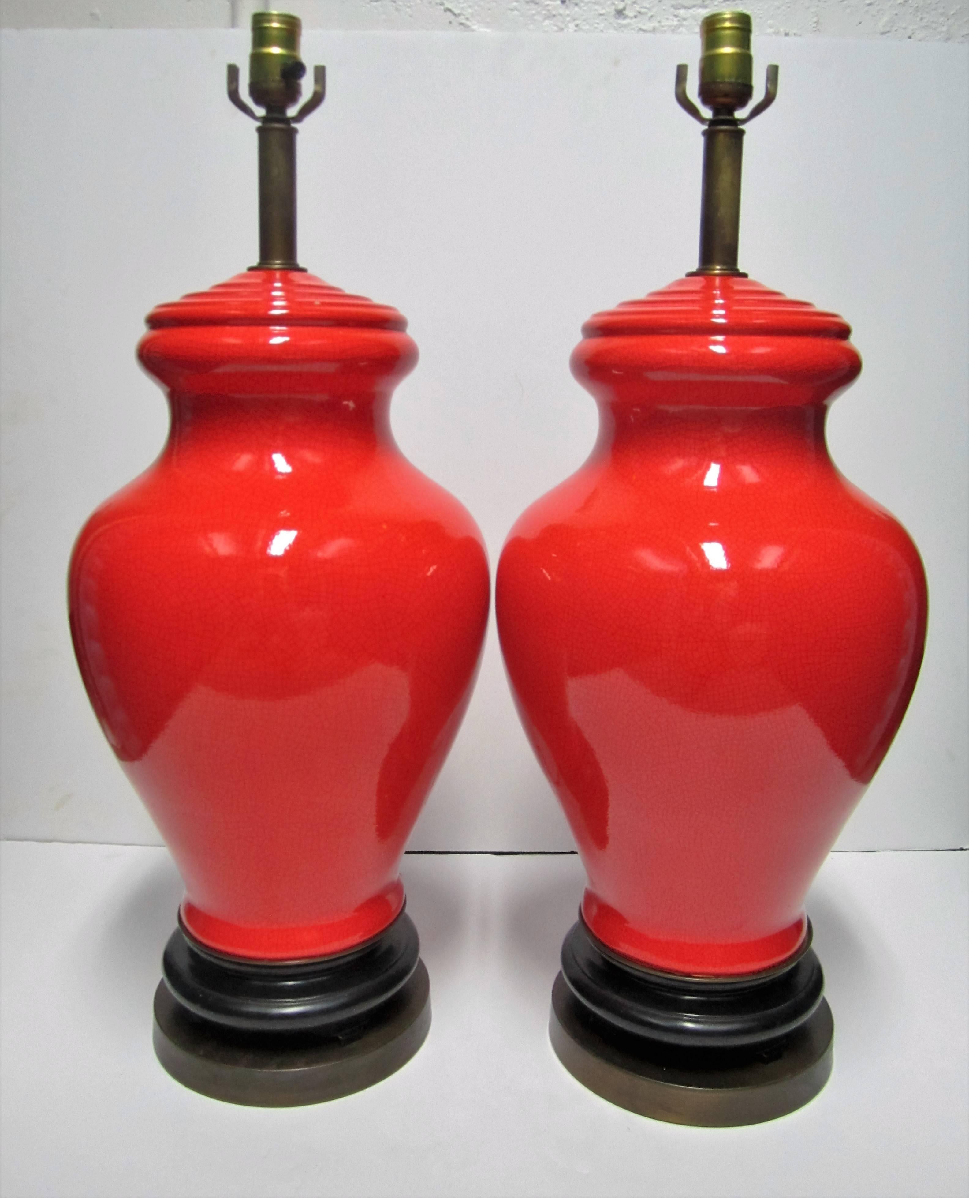 A stunning and large pair of 'geranium' red or bright red 'ginger jar' ceramic pottery table lamps with 'crackle' design on black lacquer wood and brass bases, circa 1970s. See image #5 for size perspective. In fine working order. 

Measurements