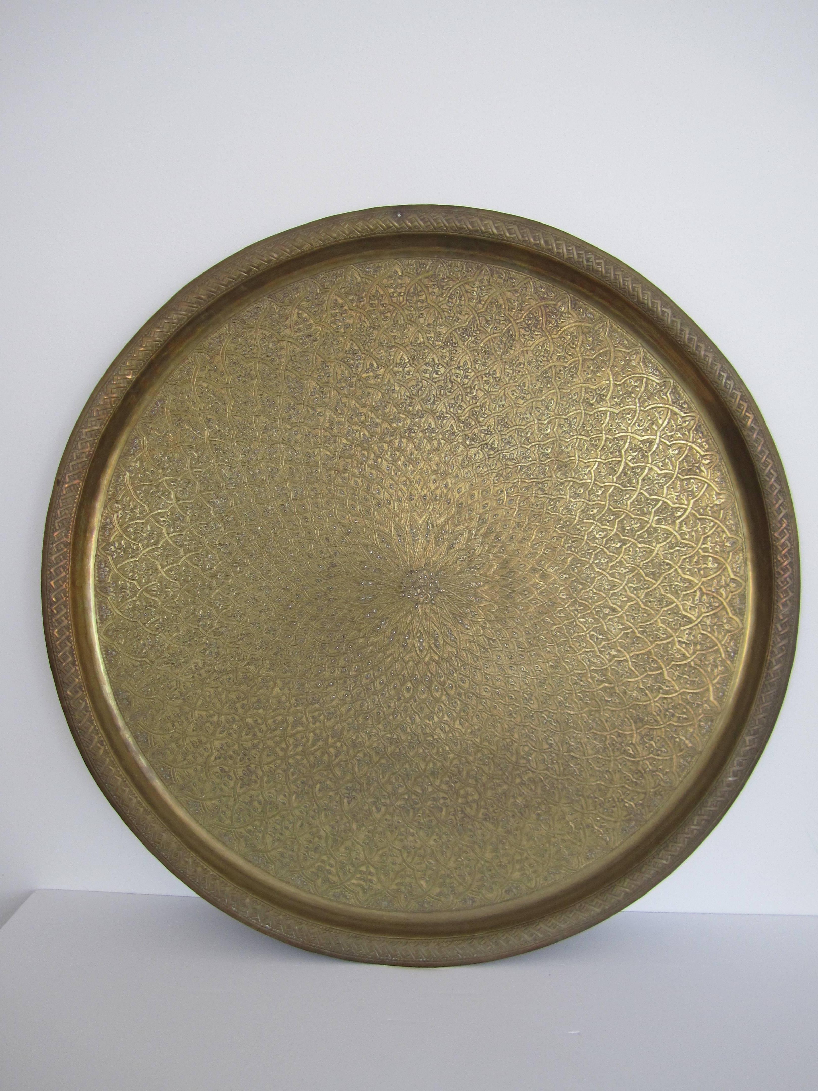 A large vintage round brass Middle Eastern serving tray with embossed decorative design. Circa 1970s. Measurement: 26