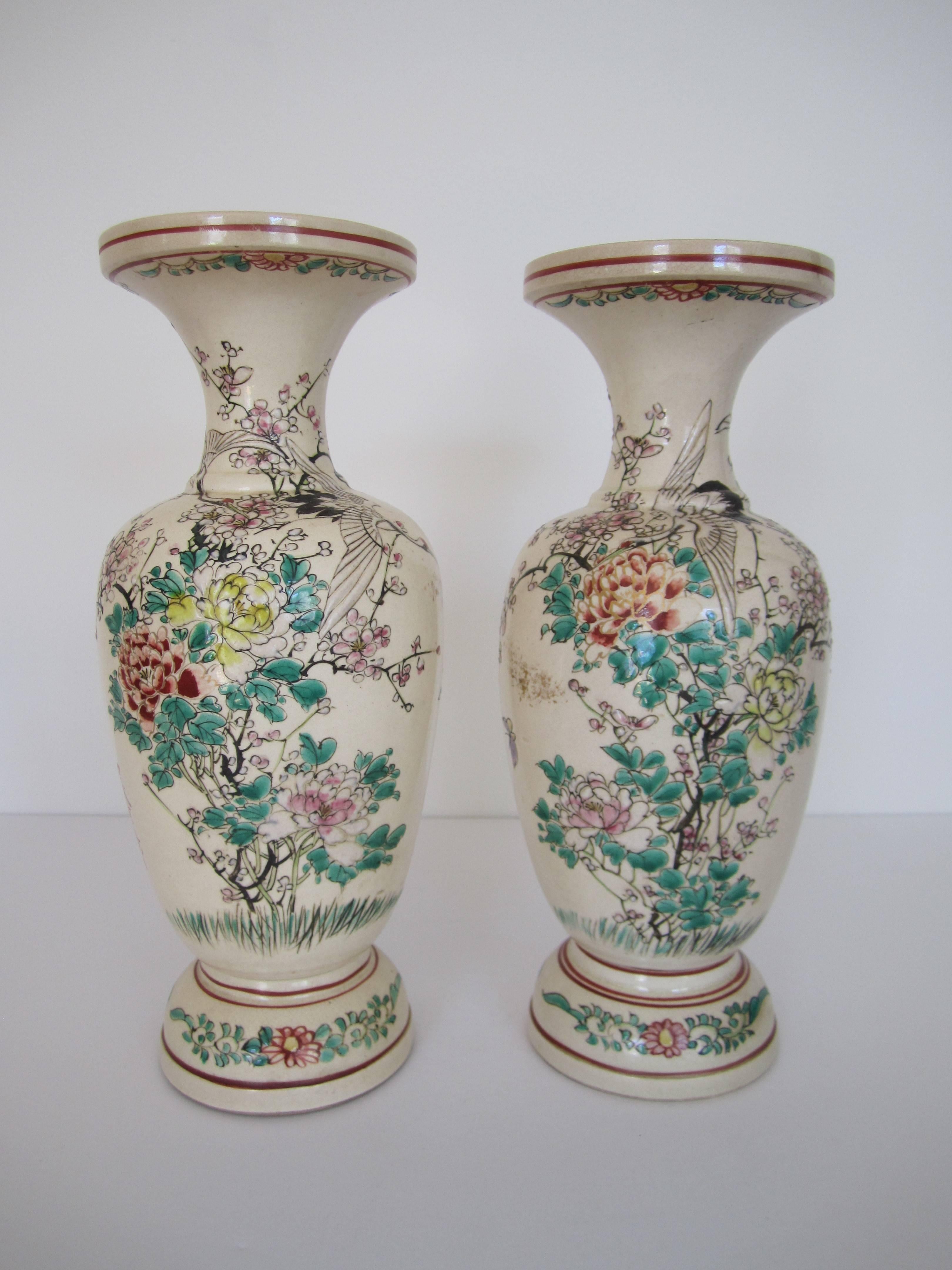 A beautiful pair of Japanese earthenware 'bisque' colored vases with a raised floral, butterfly and 'phoenix' bird relief, circa mid-20th century, Japan. Both vases signed on side as shown in image #7. Colors include green, red, blue, black, pink