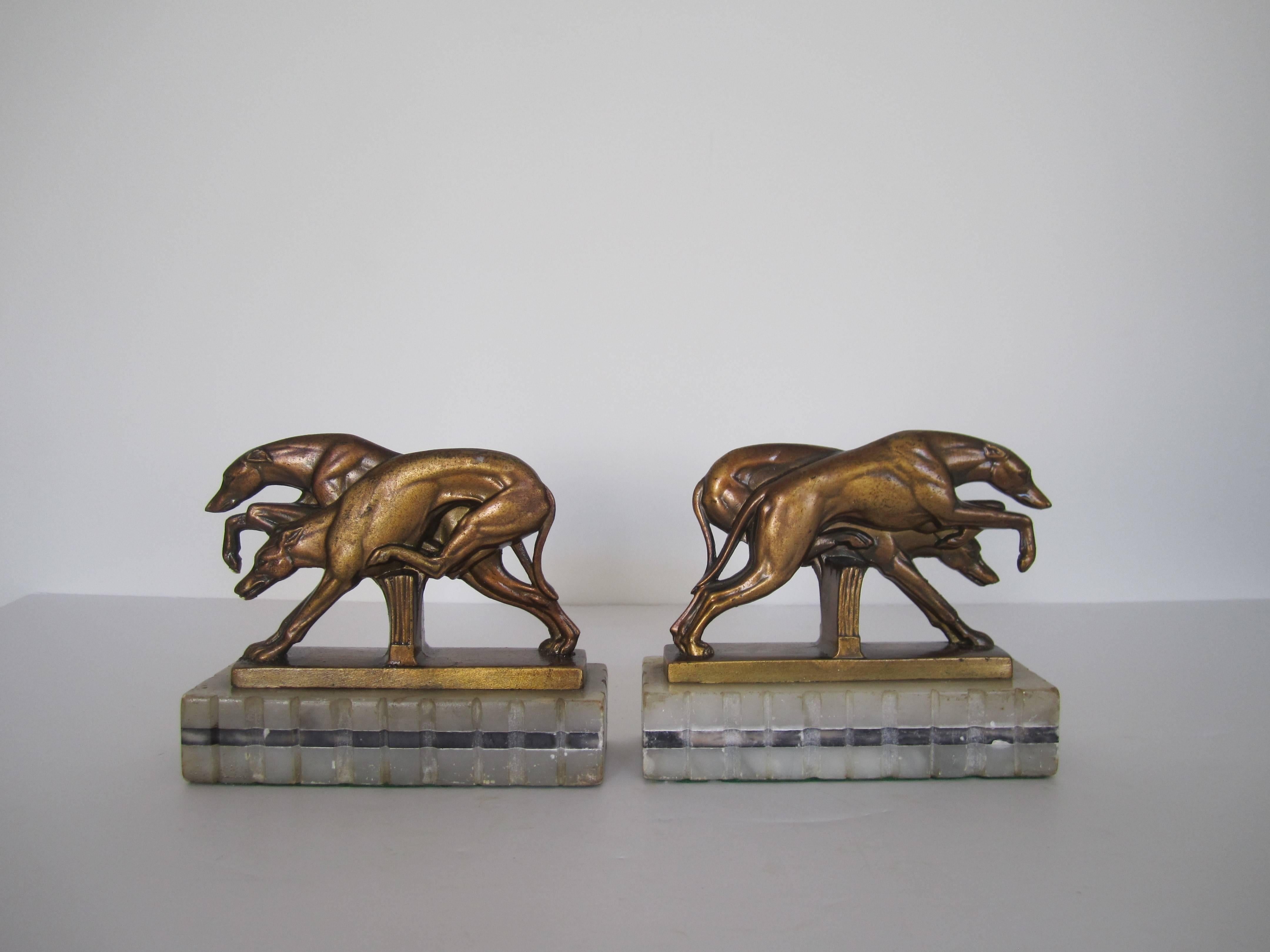 A beautiful pair of period Art Deco greyhound dog sculptures bookends on black and white marble bases, 1920s. Dogs pictured in motion atop rectangular ribbed white and back marble bases. Pair available here online. By request, pair can be made