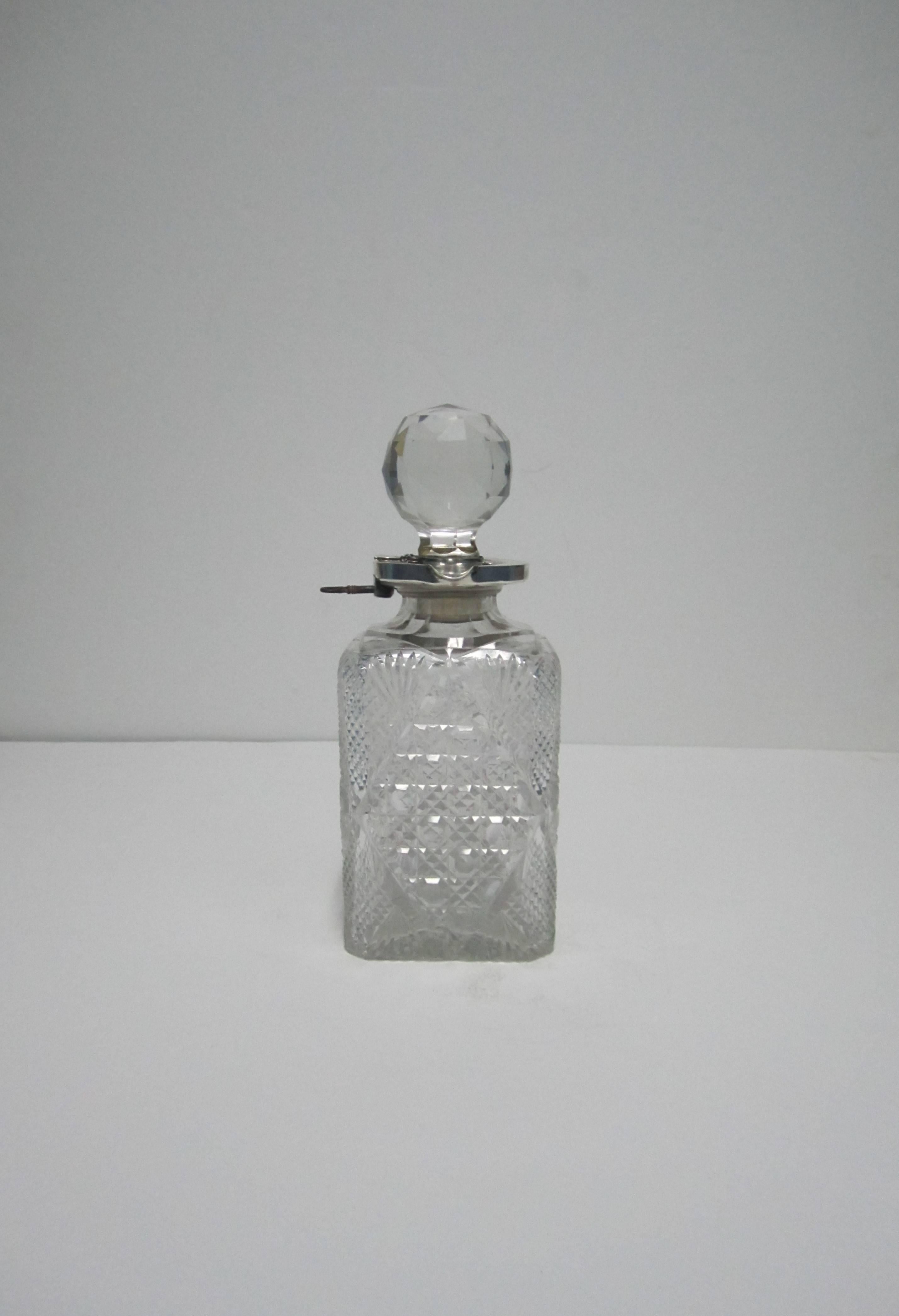 Beautiful and substantial antique English crystal and sterling silver spirit/liquor decanter with lock and key, circa early 20th Century, England. Decanter has a multifaceted round cut crystal stopper with a mounted sterling silver stopper, neck,