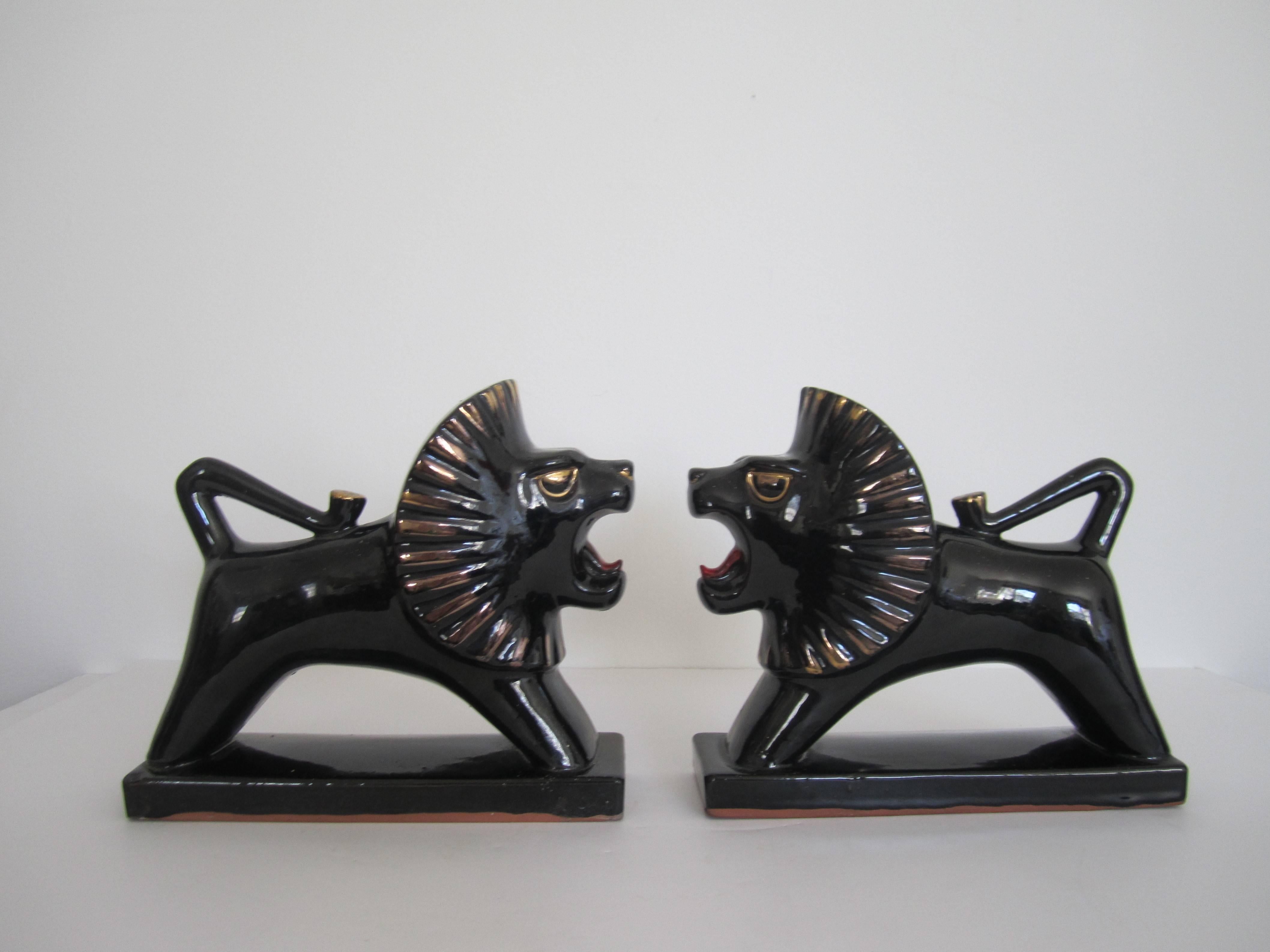 A vintage pair of Art Deco black and gold 'growling' Lion bookends or animal sculptures/decorative objects in black and gold and with red tongues. Pair are glazed terracotta. Dimensions: 6.5