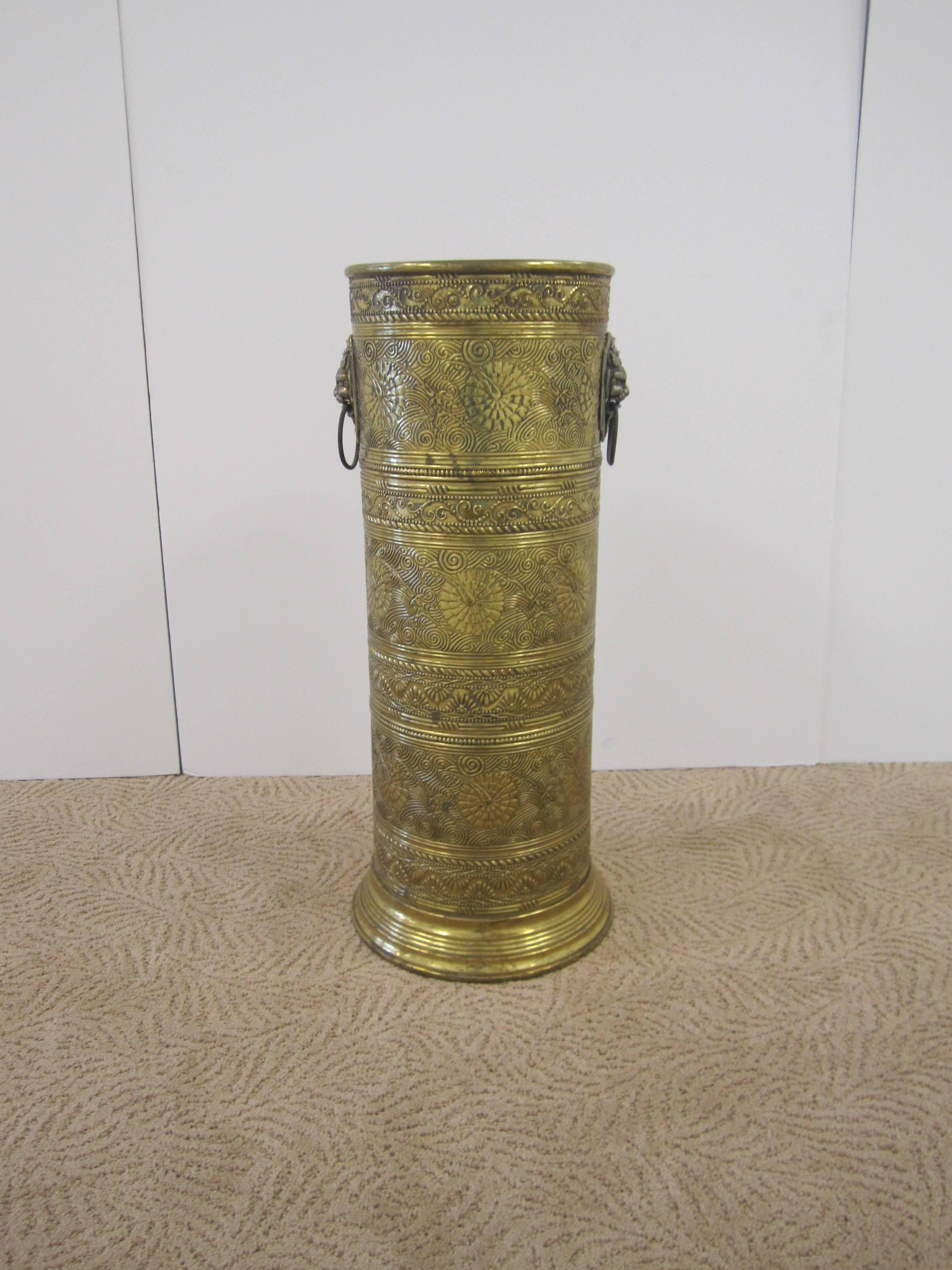 A vintage brass umbrella stand with embossed detailing, ribbed base and decorative lion heads with ring handles on either side. Item available here online. By request, item can be made available by appointment to the trade (in New York).