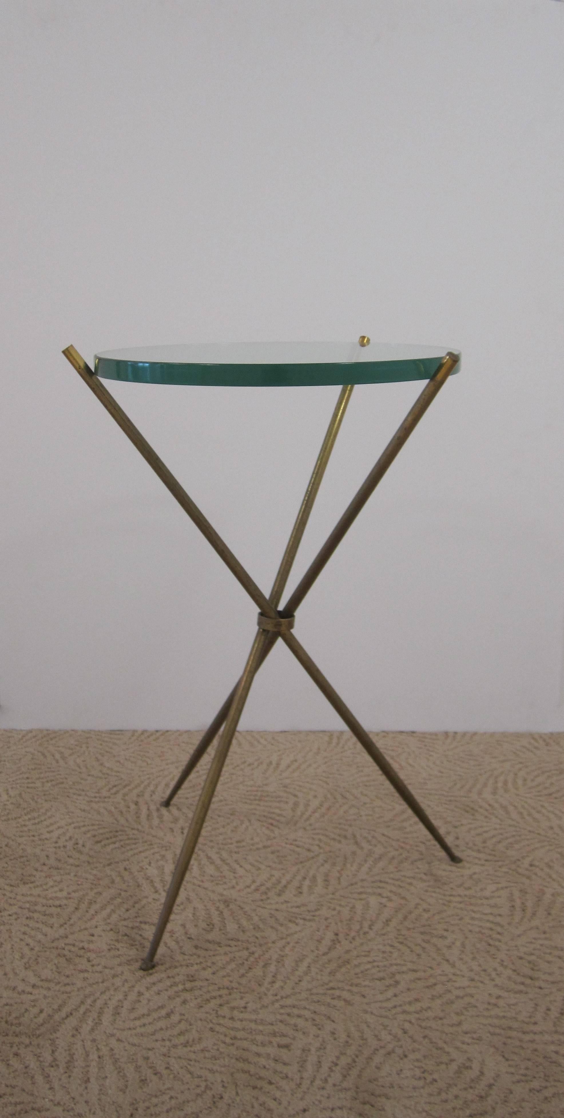 A vintage Modern Italian brass and glass tripod side table. Round table glass is 3/4 inch thick, held by a brass tripod base with tapered legs, circa 1960s, Italy. In the style of Italian designer Gio Ponti.  

Measurements include: approx. 22