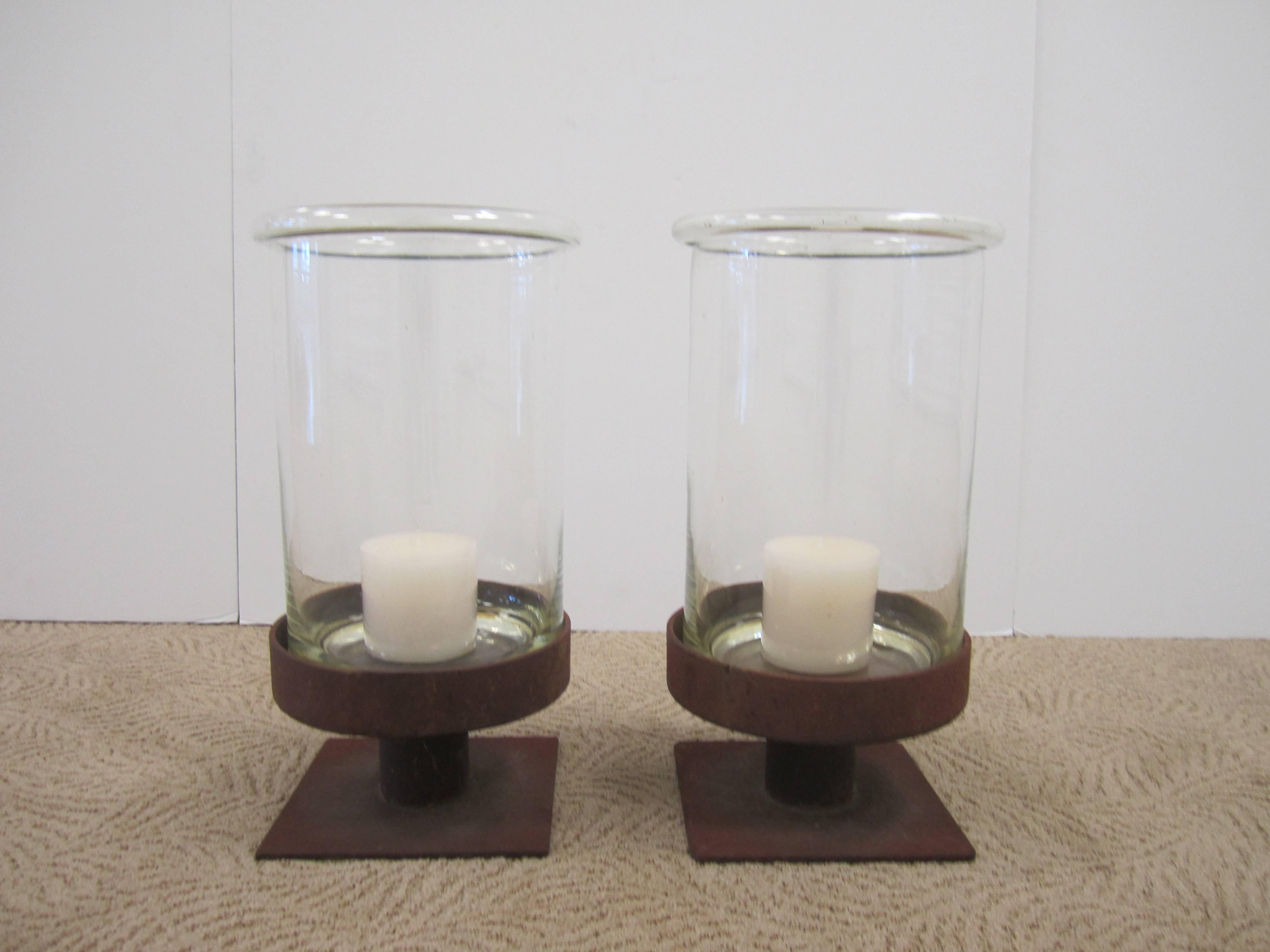 Pair/set available here for $1250
A substantial pair of vintage Modern style European glass and iron hurricane candle lamps. Bases are weathered iron, and 'hurricane' vessel is glass; glass is beautifully made with a smooth folded lip or rim.