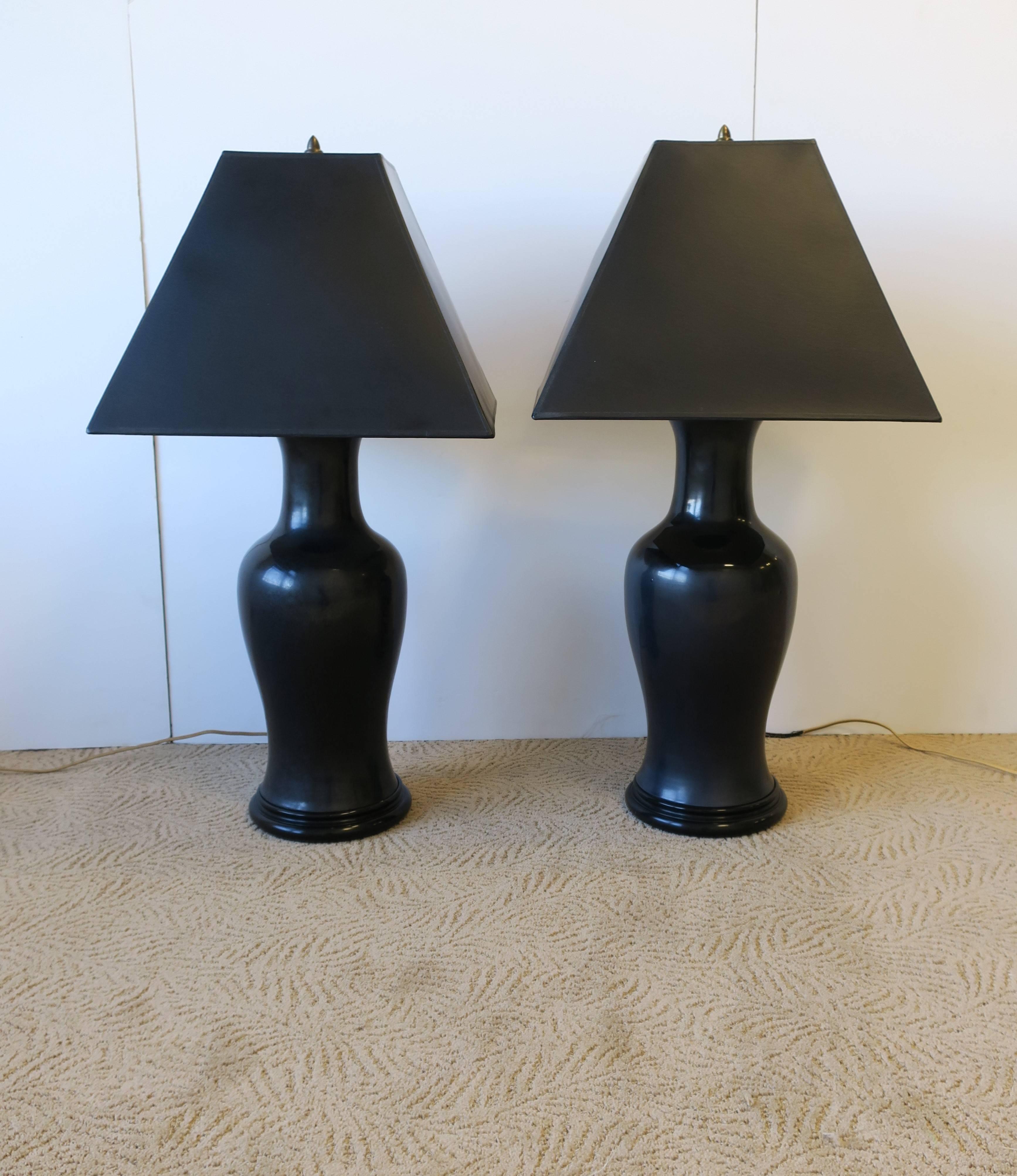 A stunning and substantial pair of black ceramic pottery 'ginger jar' table lamps with brass hardware and black lacquered wood bases, circa 1970s. Lamps hold two bulbs each with on/off on pull chains. Very good condition as shown in images.