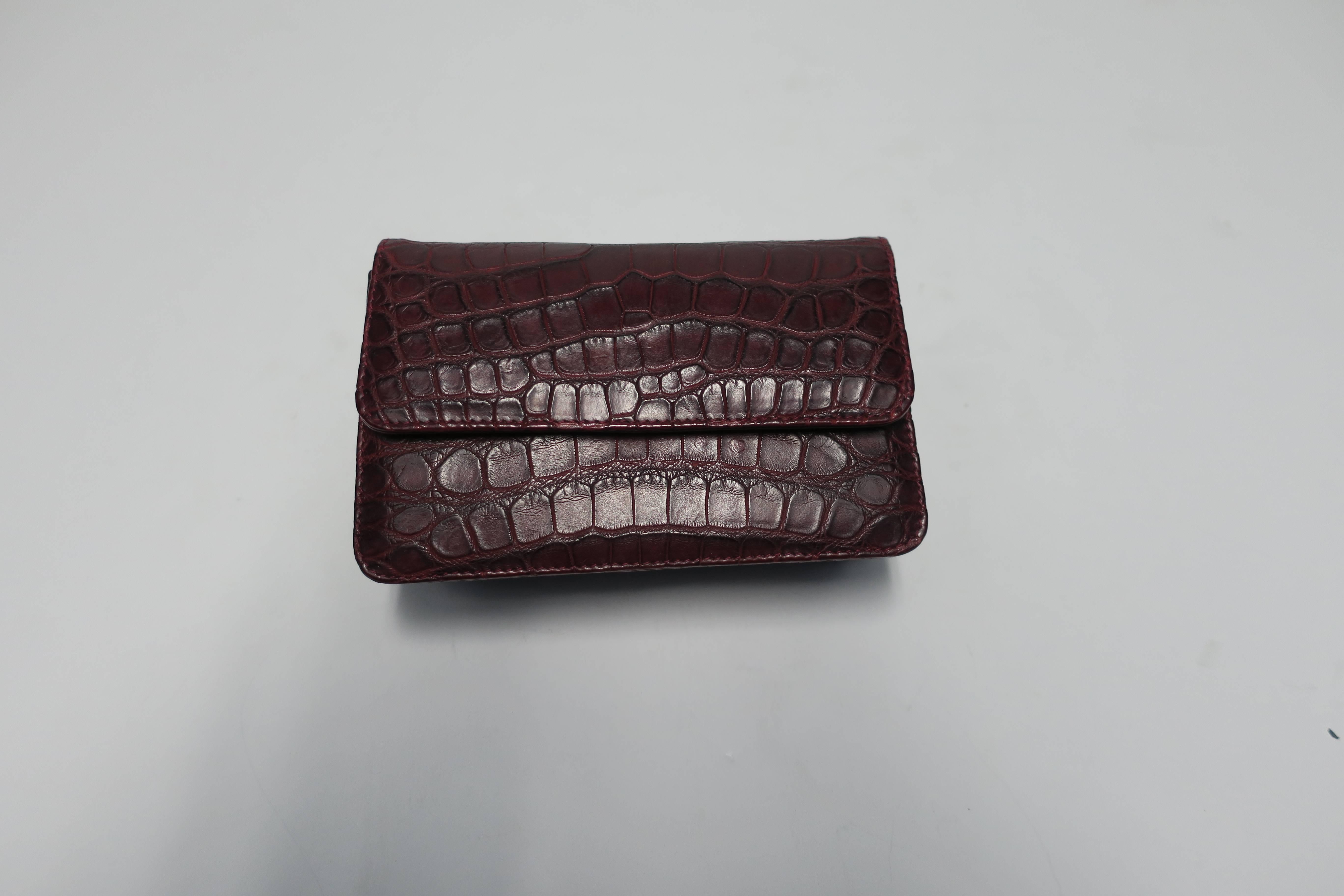 A beautiful Italian made leather crocodile embossed pattern handbag in burgundy red. Handbag can be used as a 'cross-body' bag by attaching it's removable strap, or used as a clutch. Bag has two compartments, plus a zip pouch area and a magnetic
