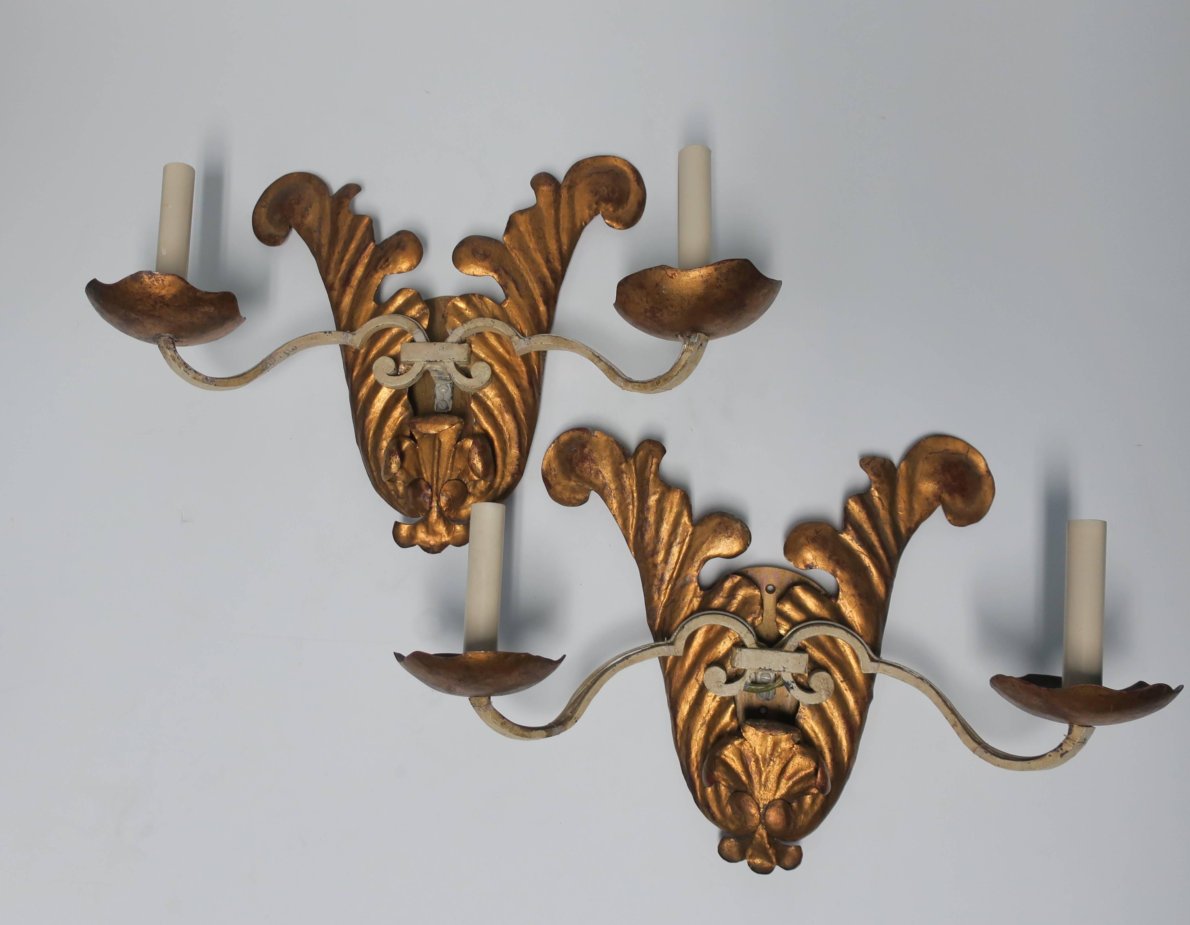 A beautiful vintage pair of enameled white iron and copper gilt tole sconces with two lights each. Wired for U.S. electric. 

Sconces measure 18.5 in. W x 12.5 in. H x 6.75 in. D. 

