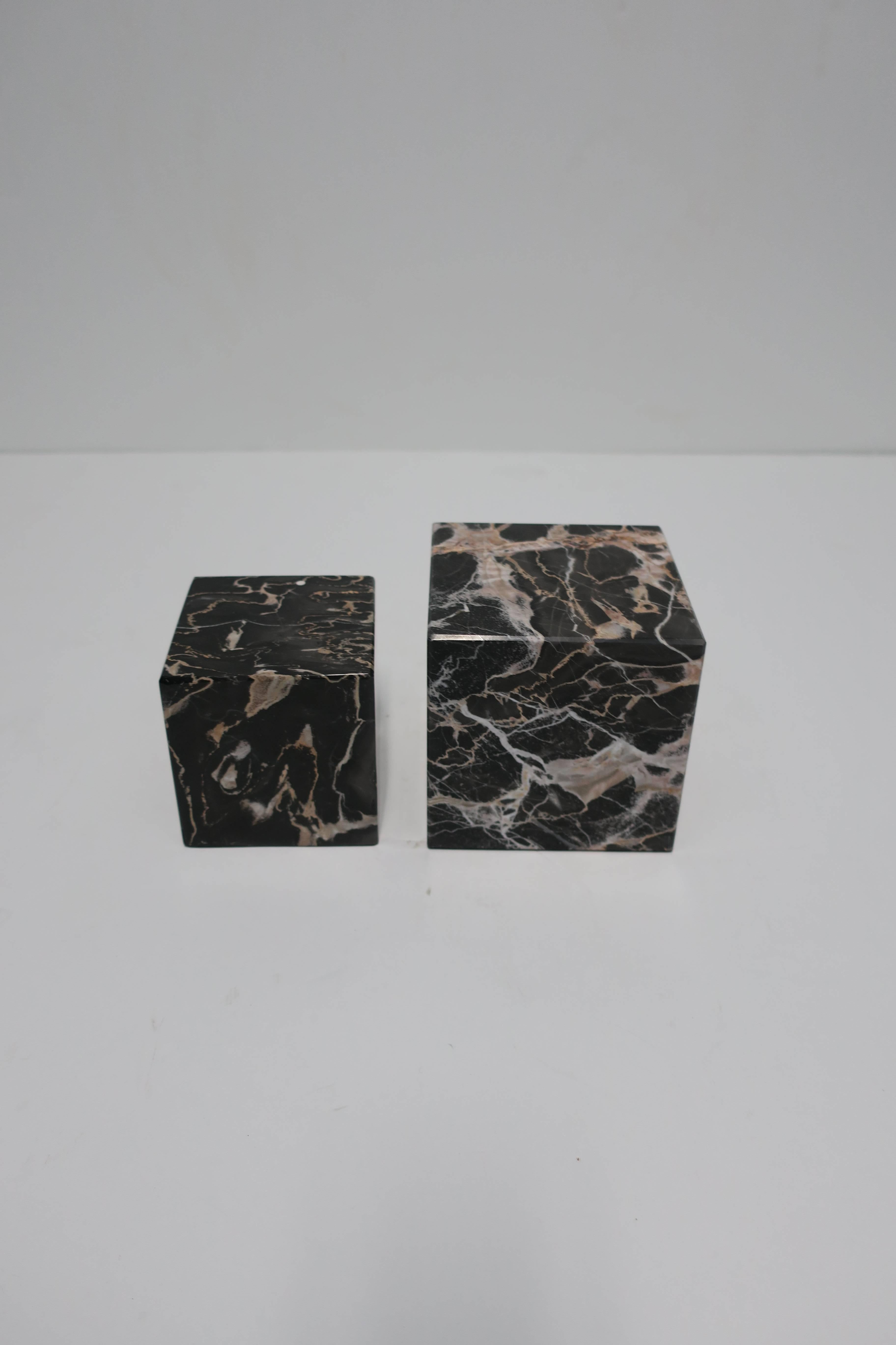 A pair of vintage black, white and rose colored marble bookends or display pedestals. Measurements: 3.25