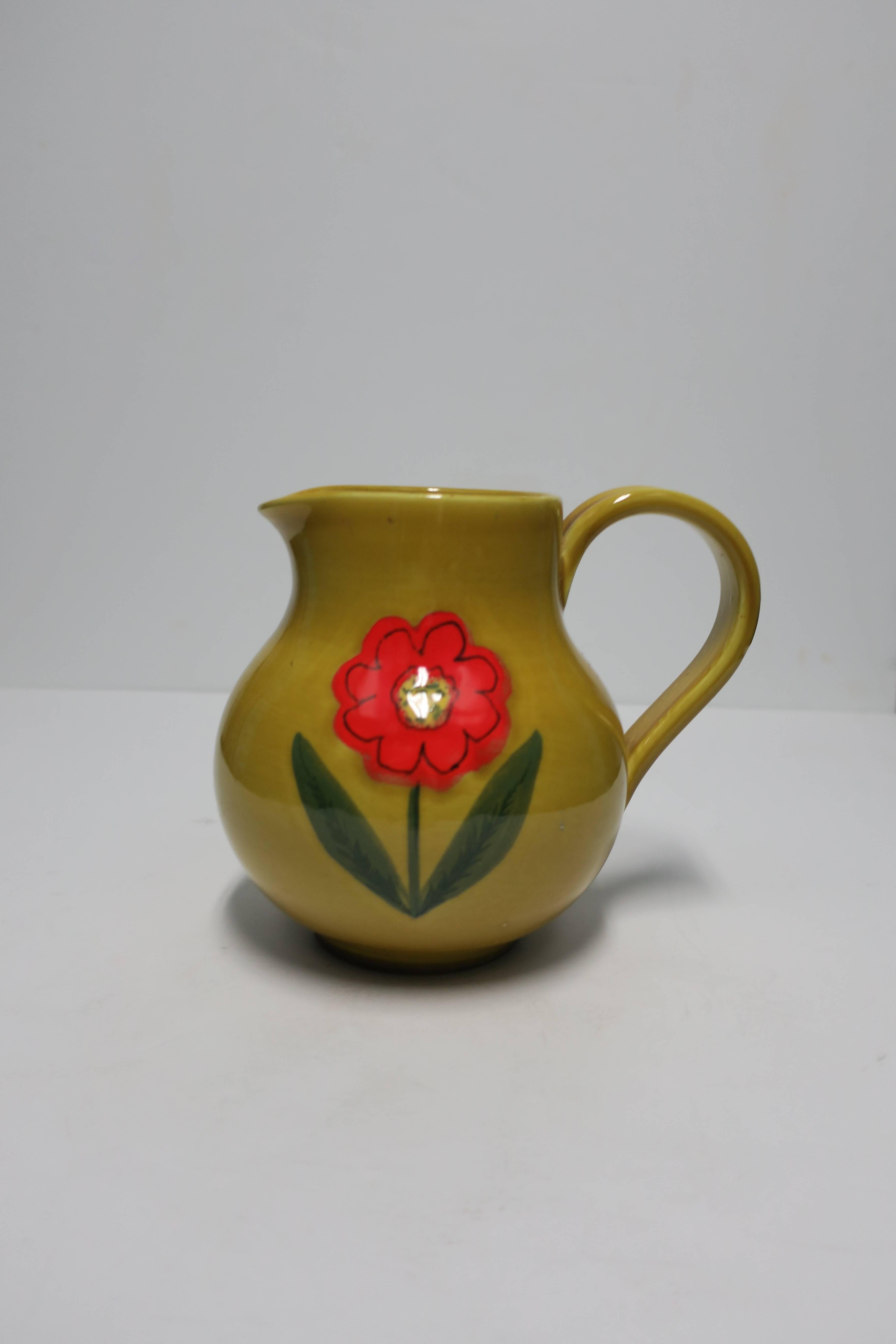 A vintage Italian ceramic pottery pitcher or vase from Italy. Pitcher/vase features a bright red flower on a dark yellow background. Numbered and marked 'Italy' on bottom as shown in image #10. 

Measures 7 in. H. 
