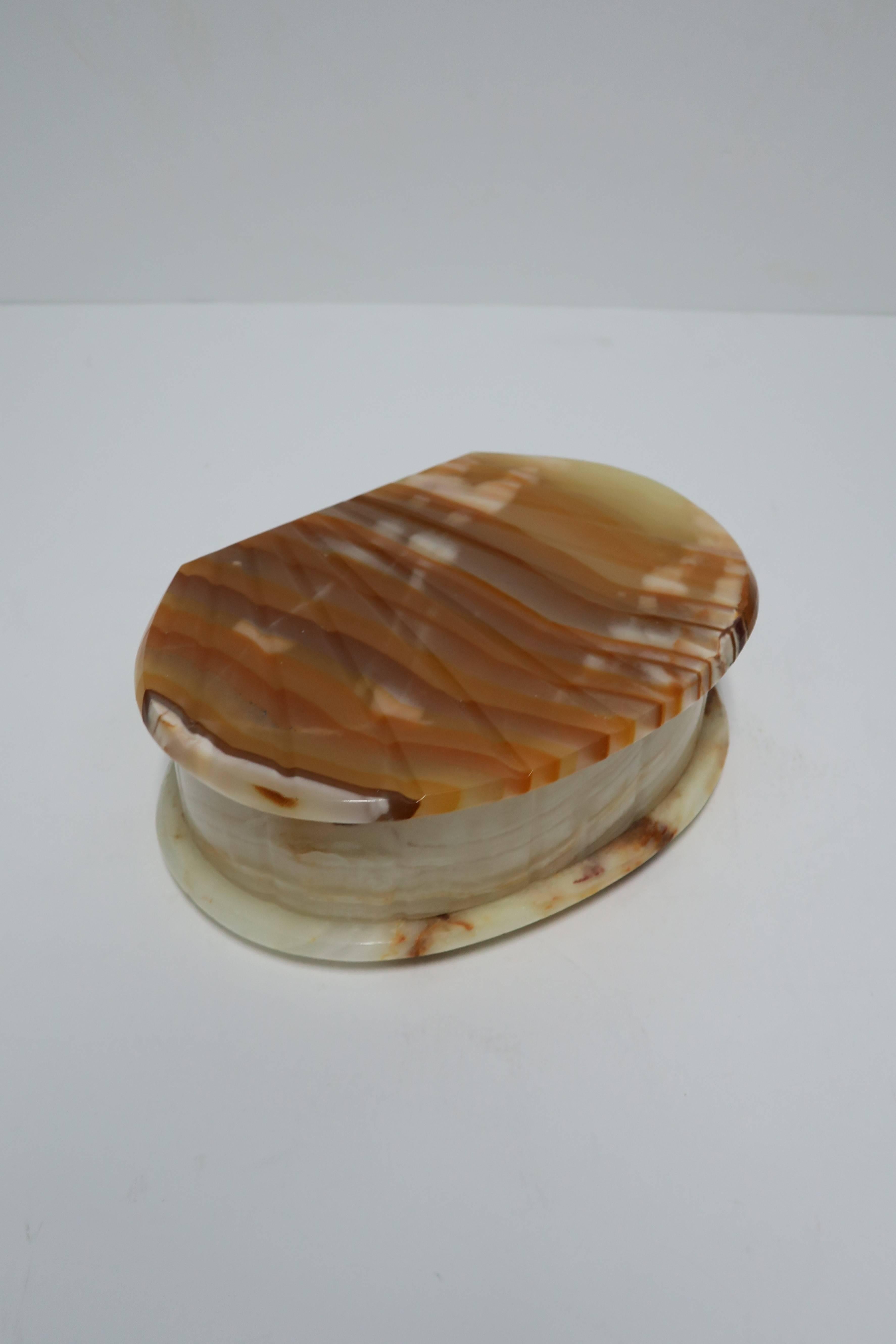 A vintage carved onyx box with hinge. Box is oval in shape with carving resembling a seashell. Colors include an organic combination of cream, off-white, light browns and caramel. 

Item available here online. By request, item can be made available