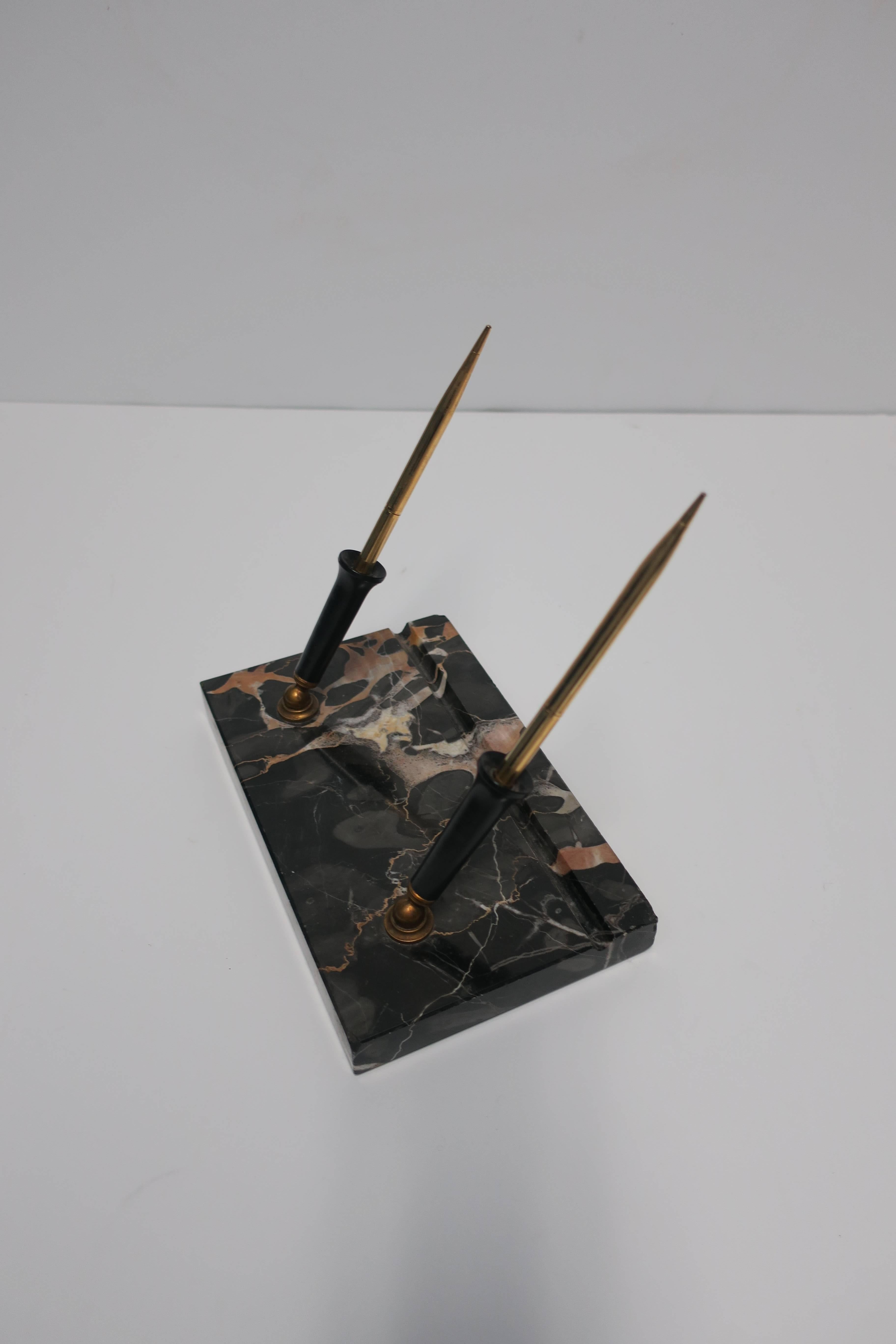 A beautiful and substantial Modern Art Deco black marble desk pen holder, with brass accents, circa 1930s. Marble is predominantly black with veining in white, tan, and flesh tones. 

Measurements include: 8 in. W x 5 in. D x 1 in. H. 

