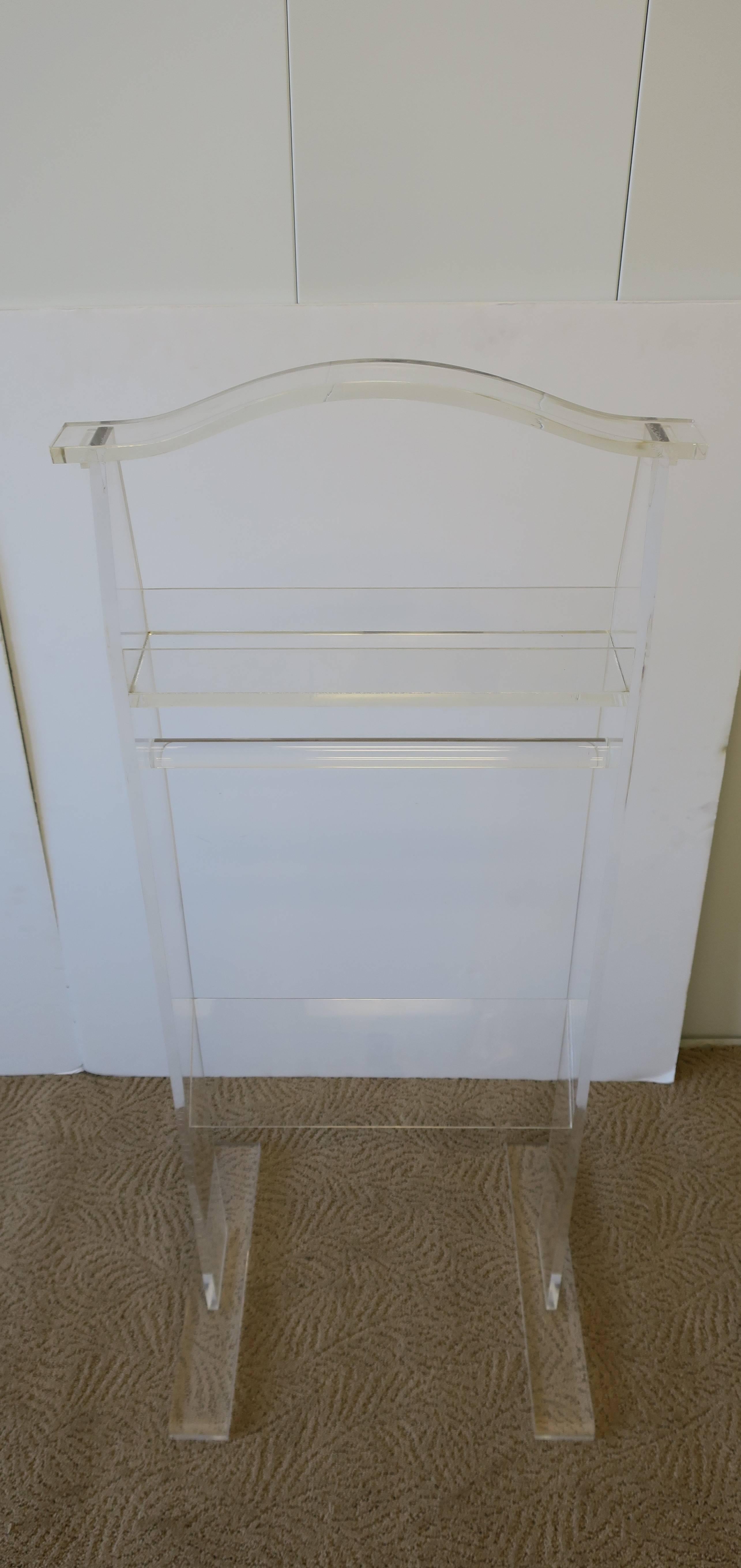 A substantial vintage Lucite clothing valet. Valet is designed to hold a jacket/top, pants (on Lucite bar), a pair of shoes, and an area to hold smaller items such as a watch, jewelry, phone, keys, etc., as show in images. Valet is circa 1970s or