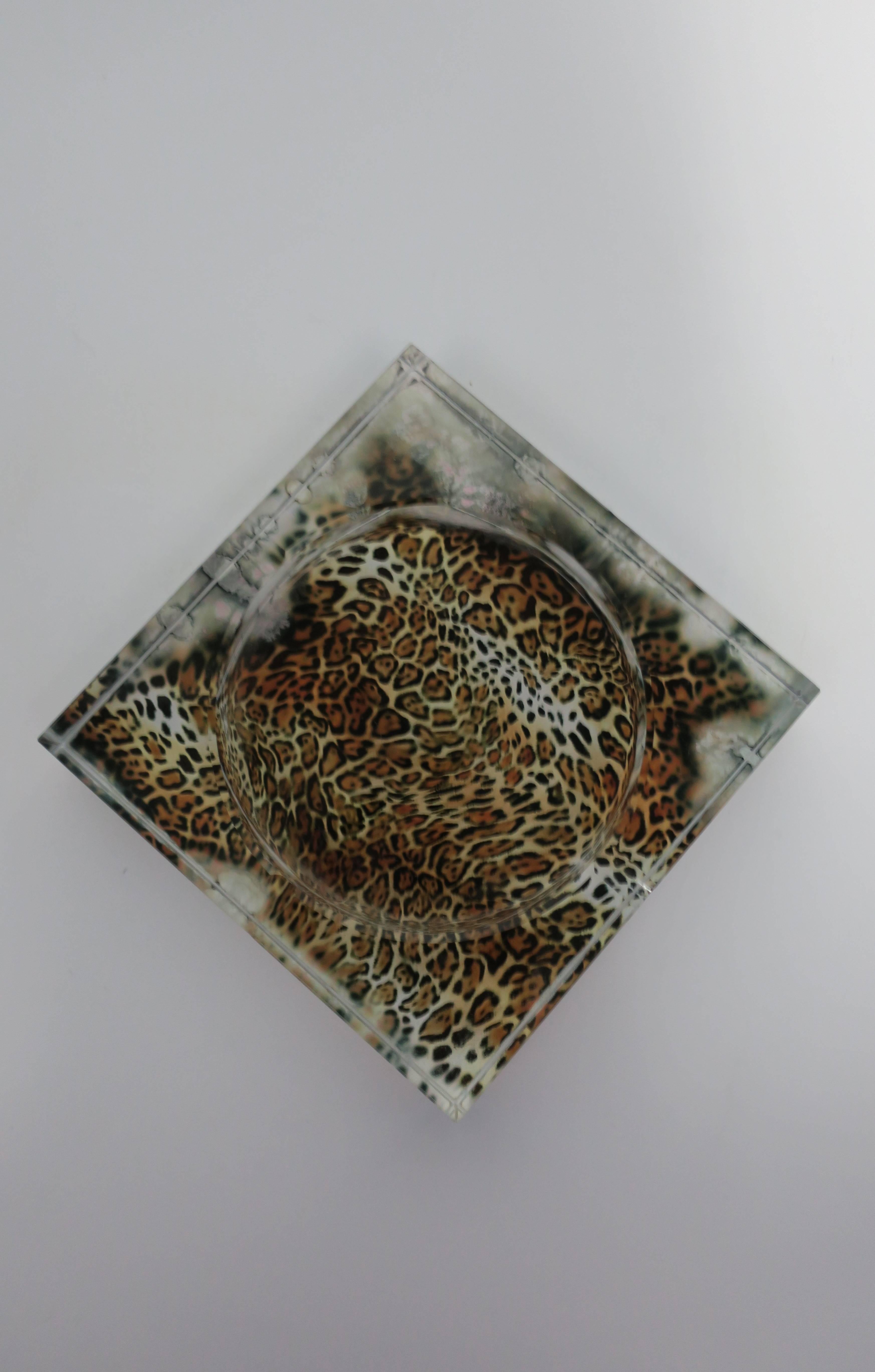 A chic clear glass vessel or ashtray decorated with a faux leopard skin bottom. Four intentional indents on top. Measures: 6
