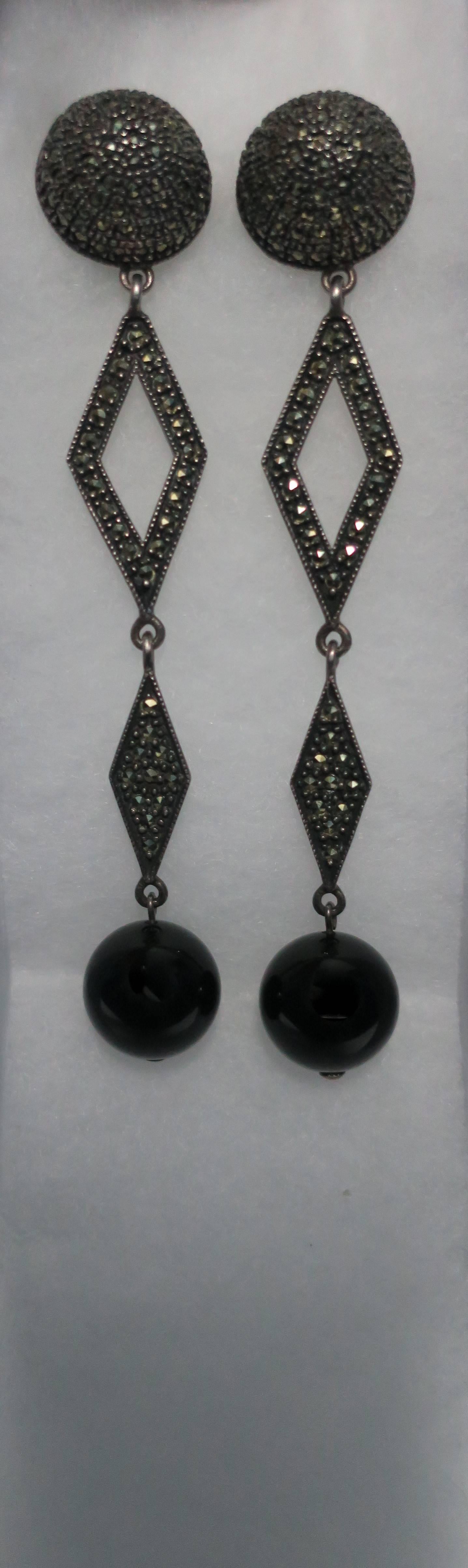 A striking and beautiful pair of long Art Deco style black onyx, sterling silver, and marcasite earrings. Earring are for pierced ears, and are light and comfortable to wear. Marked 'Sterling' on back. 

Measures 3.75 inches long. 