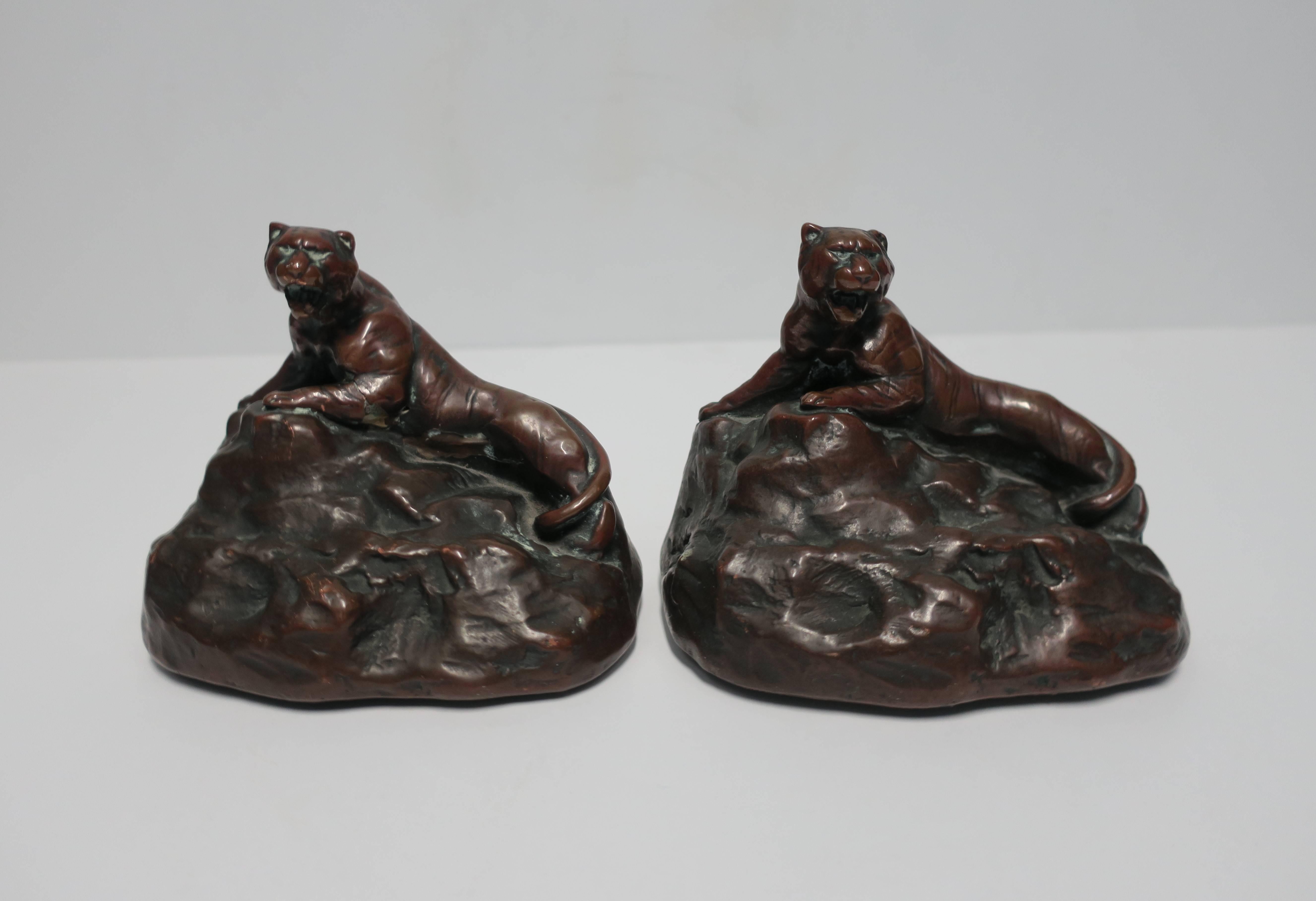 A pair of vintage tiger, leopard, or cheetah cat Art Deco style bookends, circa 1970s or earlier. Bookends show fine detail of 'growling' tiger cat situated on a boulder rock. Bookend is comprised or wrapped of a thin copper metal with patina.

  