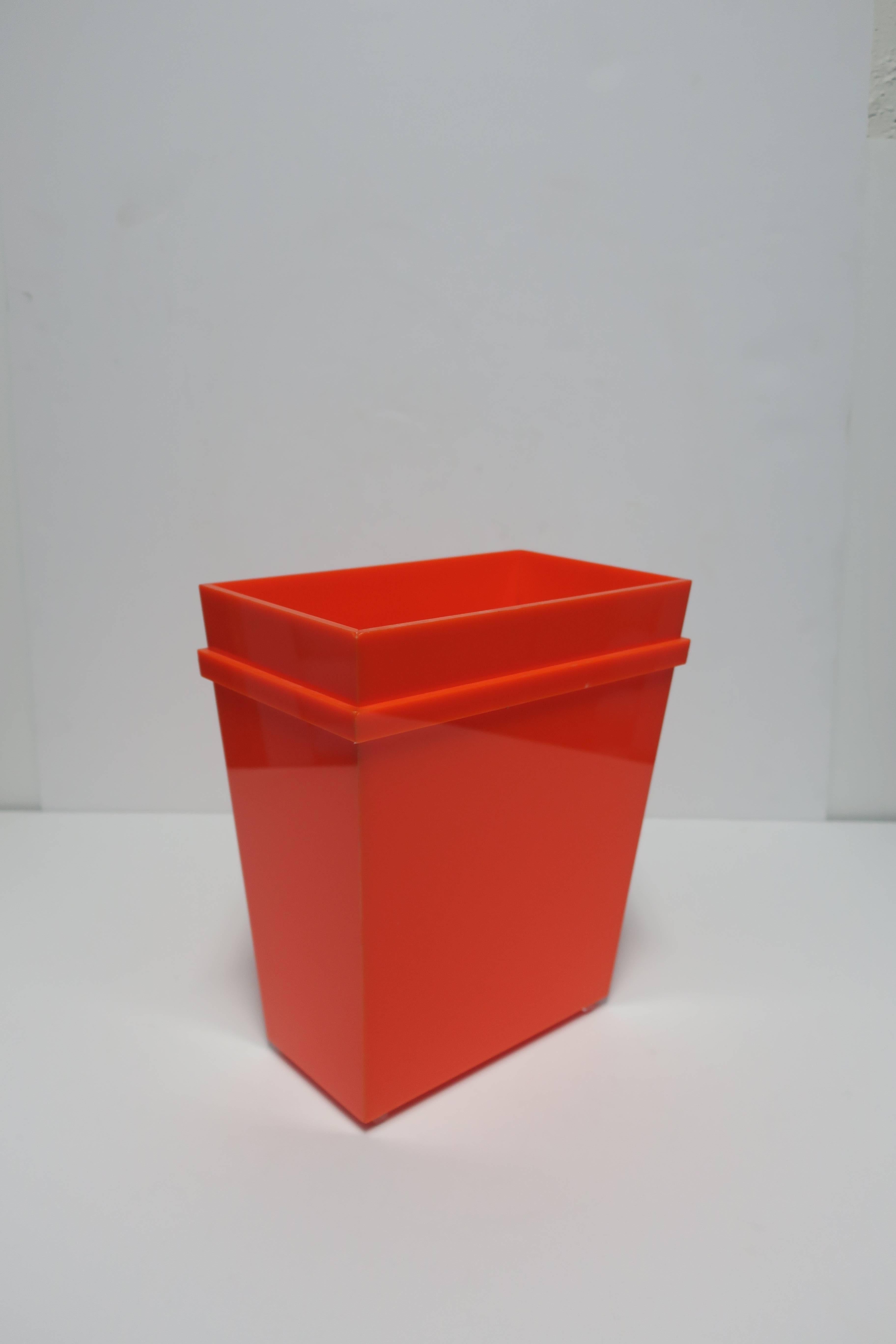 A beautiful and bright Postmodern orange acrylic rectangle wastebasket or trash can. Wastebasket has an orange acrylic band detail around and clear acrylic cylindrical feet.

Item available here online. By request, item can be made available by