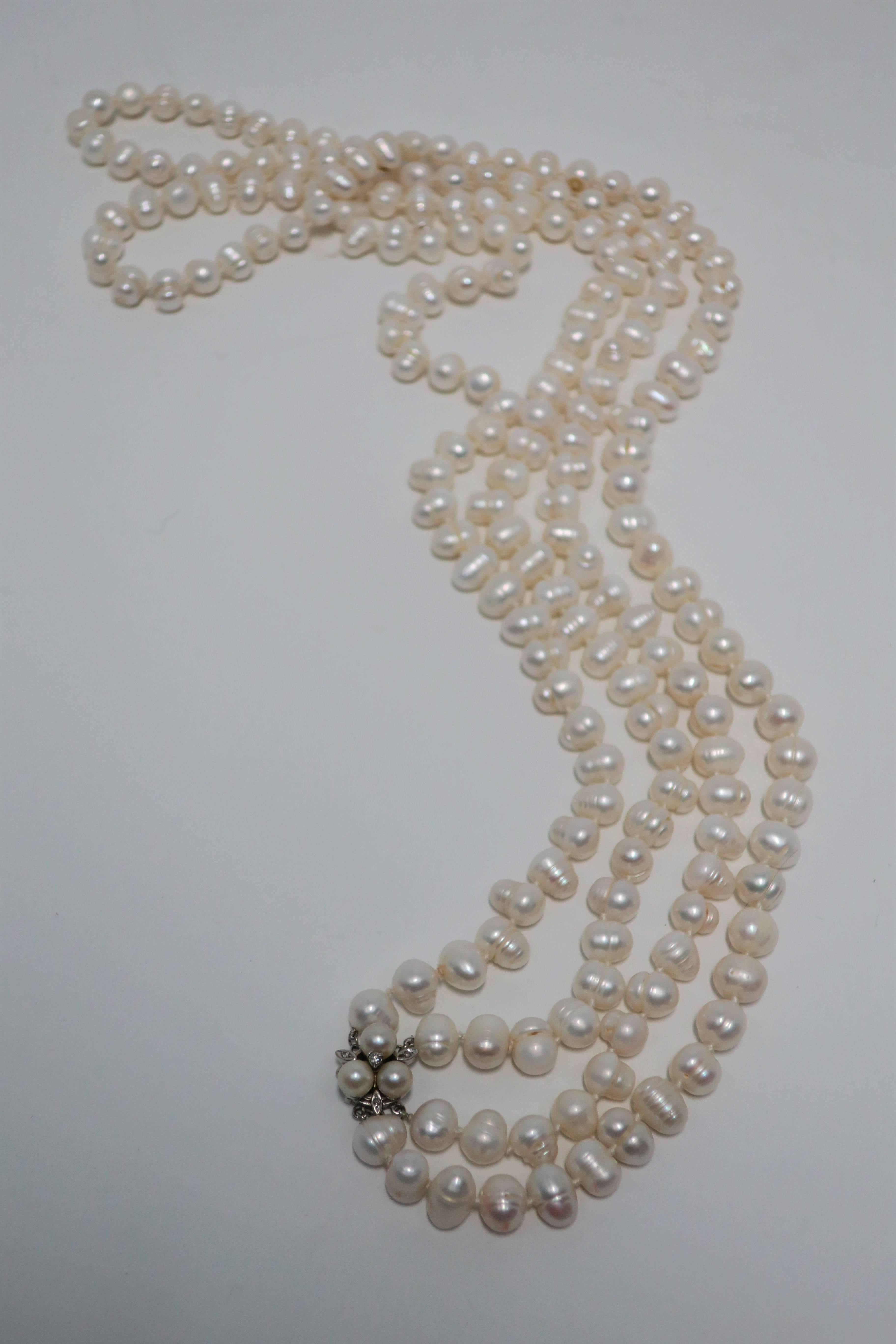 A beautiful long double strand real natural freshwater pearl necklace, with a vintage 14-karat white gold, cultured pearl, and diamond clasp. This natural freshwater pearl necklace is beautifully strung with knotting in-between each pearl. Vintage