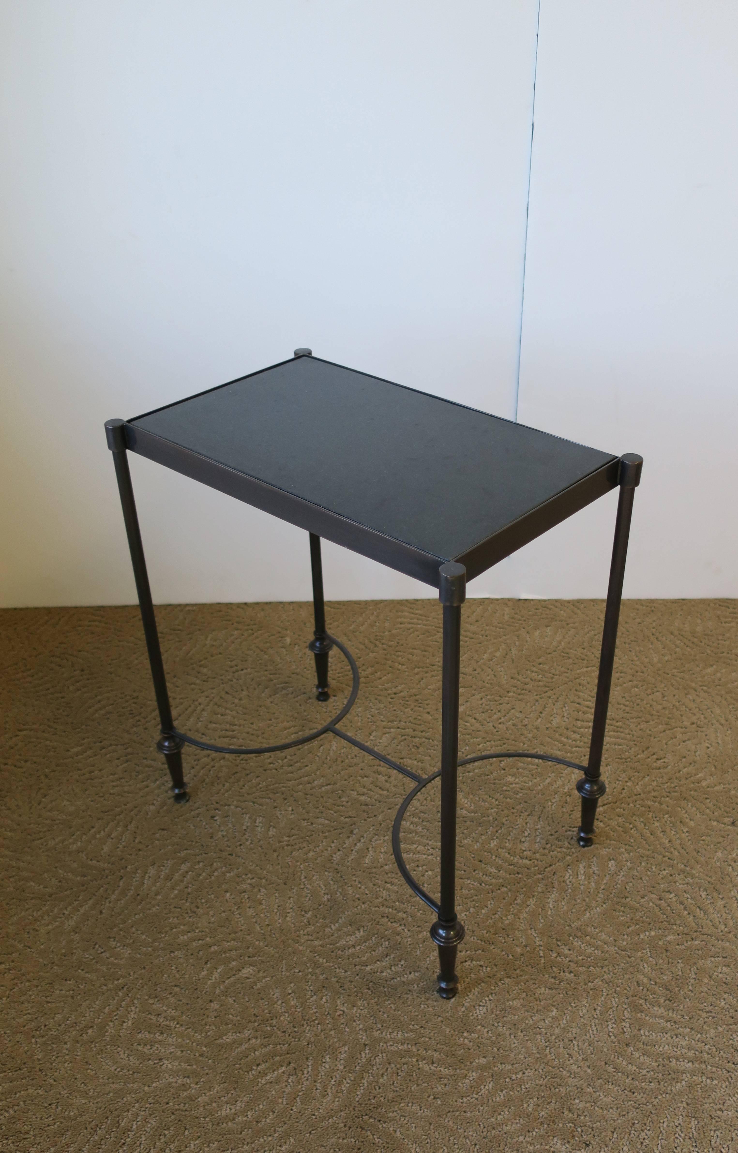 A small rectangular contemporary side or end table in the style of Maison Jansen. Frame is a dark or 'smoked' metal, inset black granite top, and stretcher base. Table measures 18.25 in. H x 16 in W x 10 in. D.

Item available here online. By