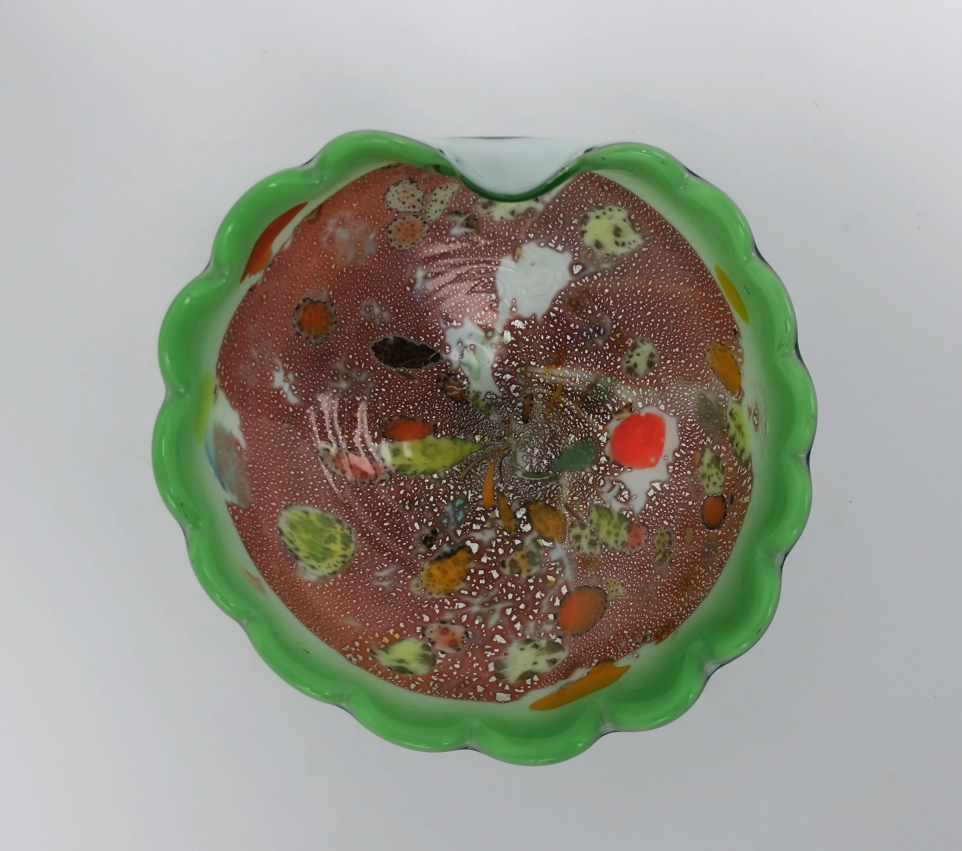 Eine schöne italienische Murano-Kunstglasschale in leuchtendem Grün mit geschwungenem Rand, ca. Mitte des 20. Jahrhunderts, Italien. Zu den Kunstglasfarben gehören: leuchtendes Grün, leuchtendes Orange, Weiß, Schwarz, Gelb und Silberflecken. Bowl