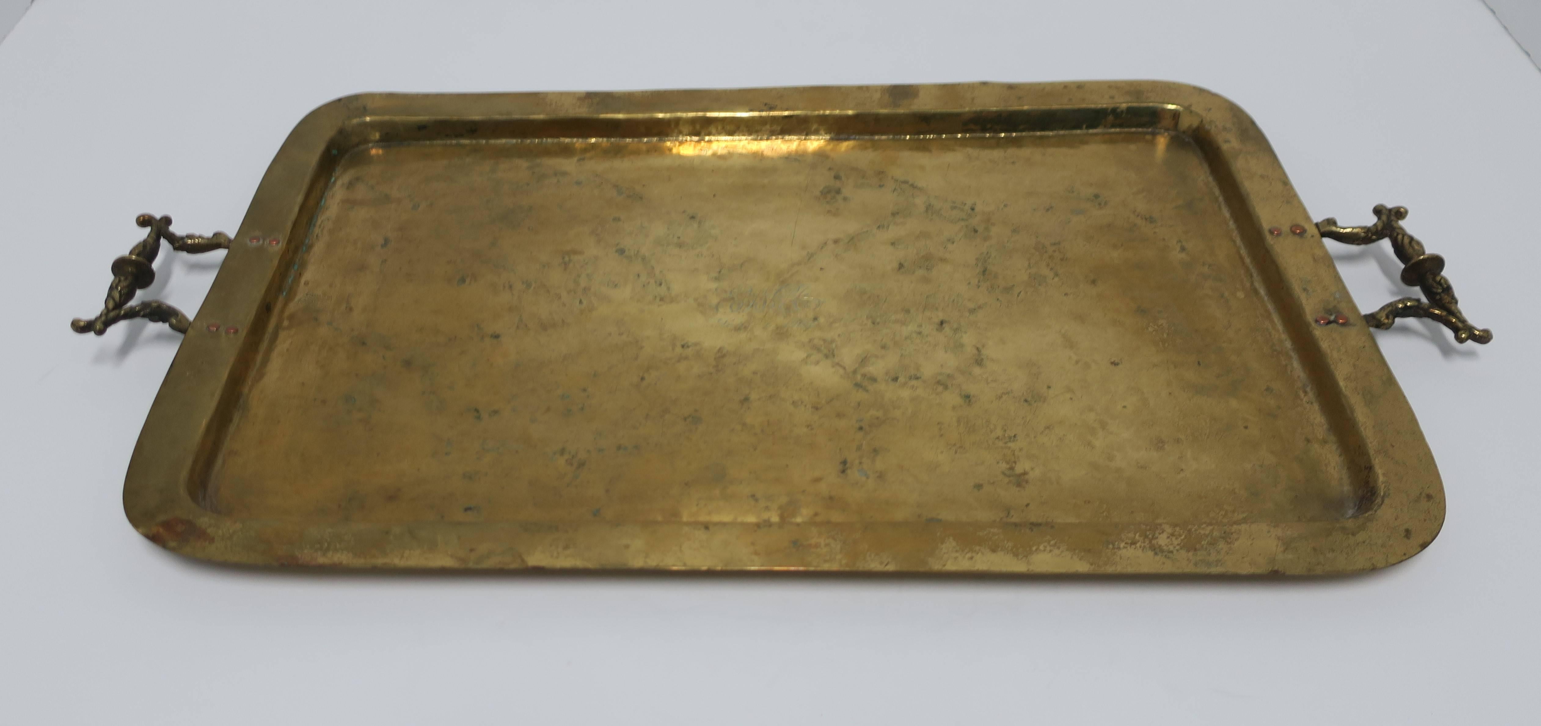 A beautiful antique brass serving tray with decorative handles, circa early 20th century. Tray has small center engraving reading: ENA, Sept. 6, 1907. Tray is embossed with maker's mark as show in image #8. 

Tray measures: 24 in. x 13.5 x .75 in