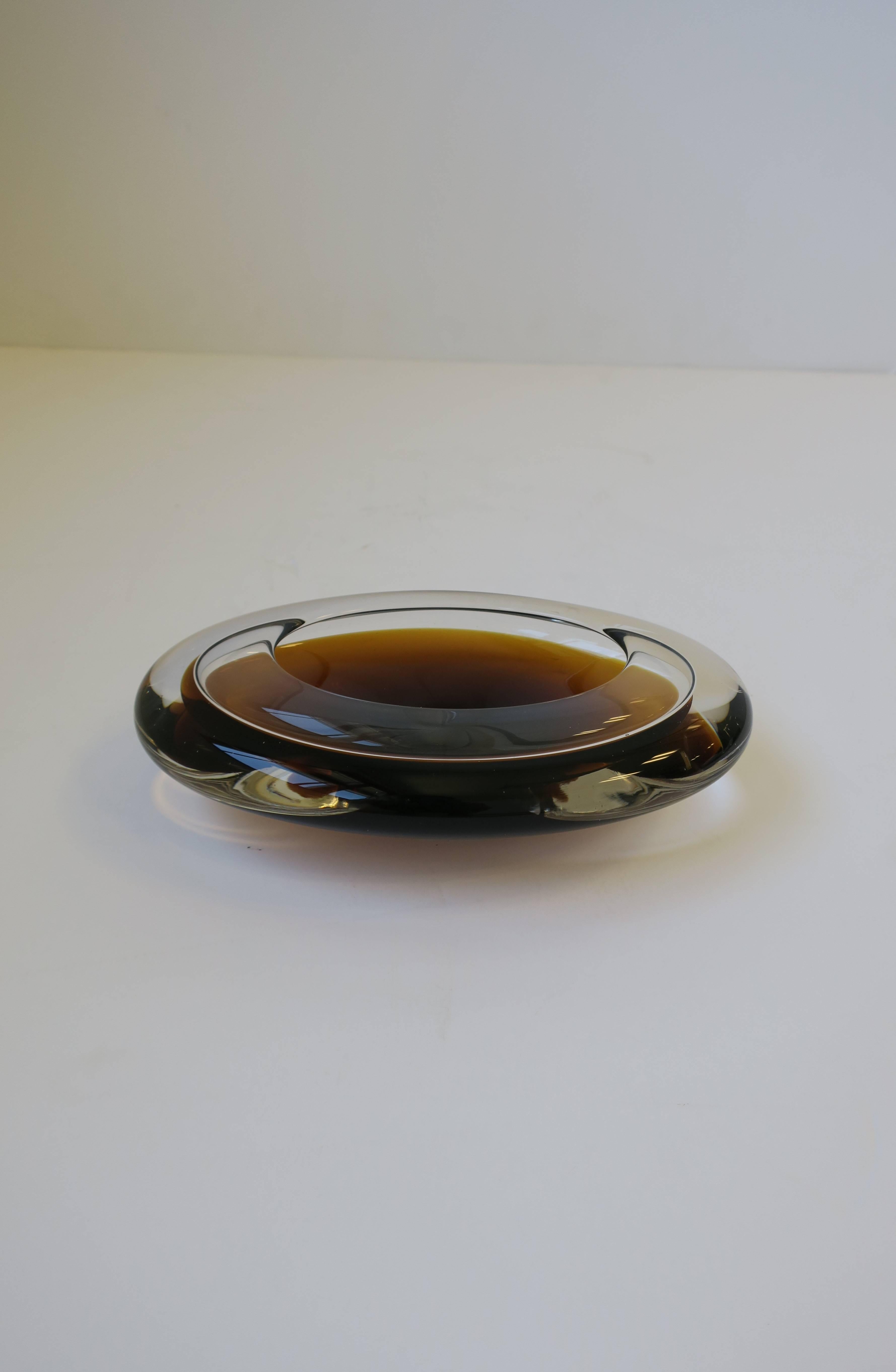 A beautiful, chic and substantial oval European 1970s Modern art glass bowl. Glass bowl is hand-blown; colors include clear glass mixed with an amber or chocolate brown glass. 

Measures: 6 in. x 3 in. x 2 in H.

Item available here online. By