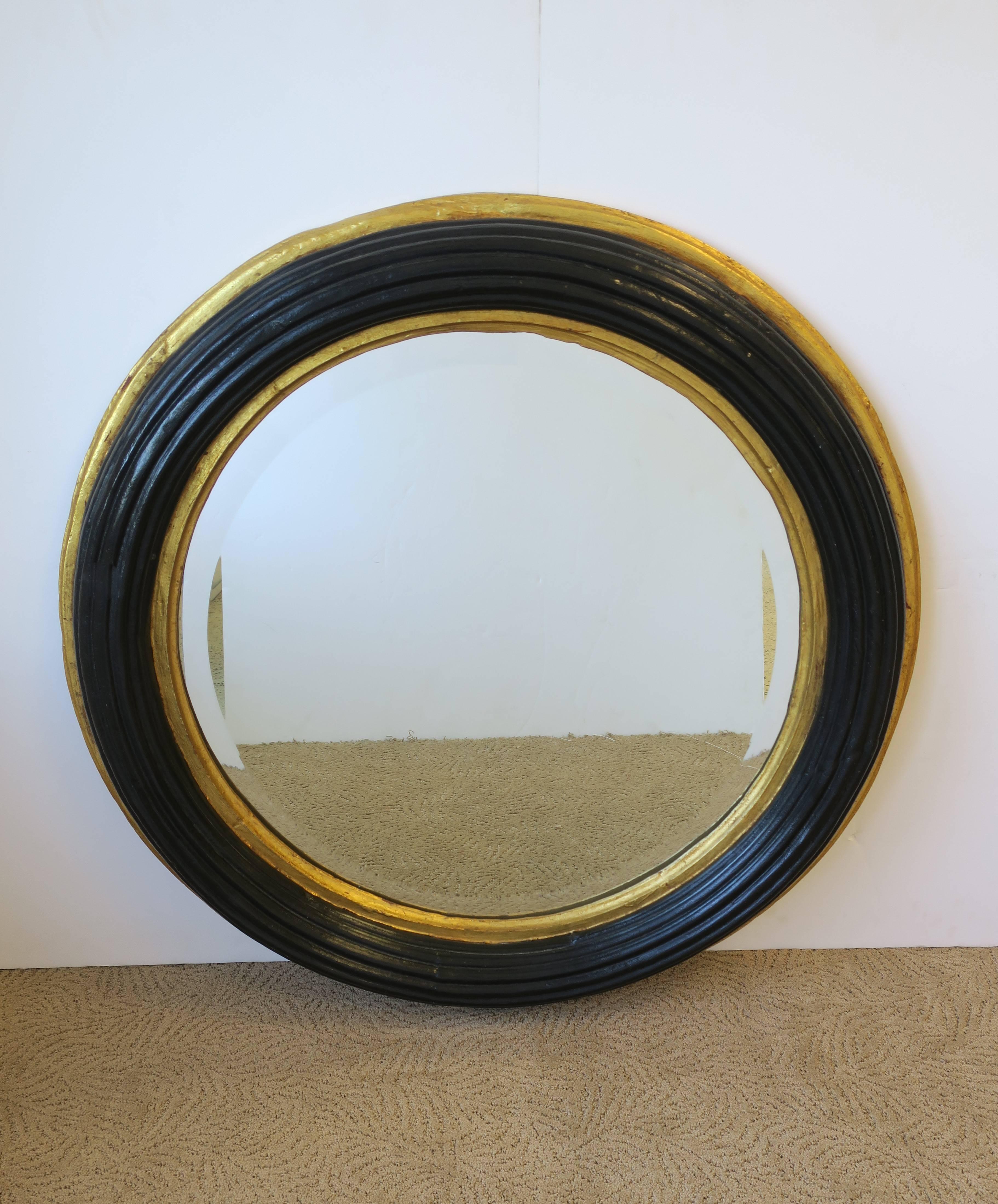 A beautiful and substantial Mid-Century round black and gold beveled wall mirror. Black lacquer paint and gold gilt paint on ribbed wood frame, surrounding beveled mirror. Bevel is approximatly 1 in. wide. 

Mirror measures: 34 in. in diameter x