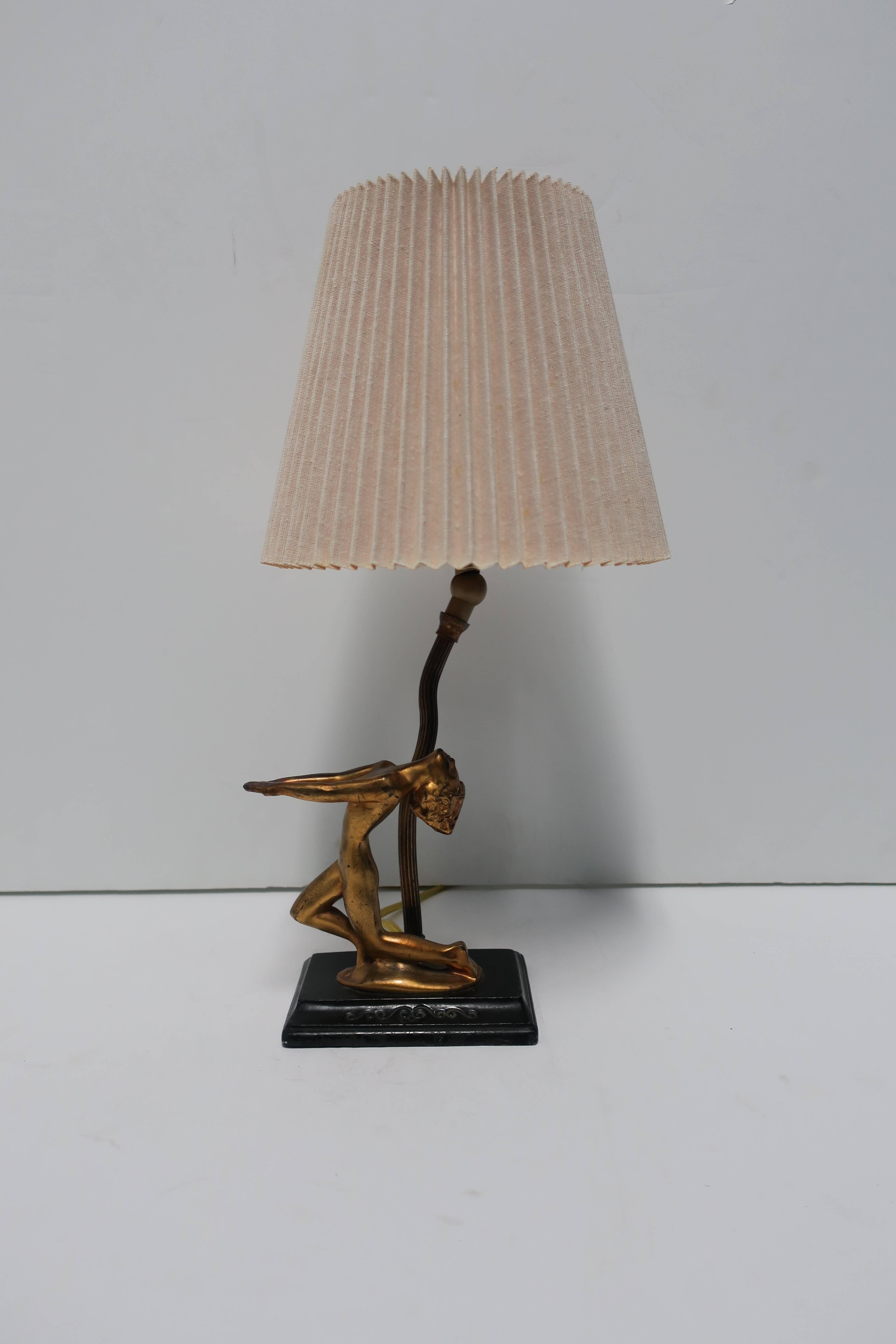 A beautiful Art Deco period black and gold gilt desk or table lamp with female sculpture figure posing on rectangular base, circa 1930s. Lamp is attributed to Frankart. Lamp has been rewired to US specifications as shown in images. Vintage pleated