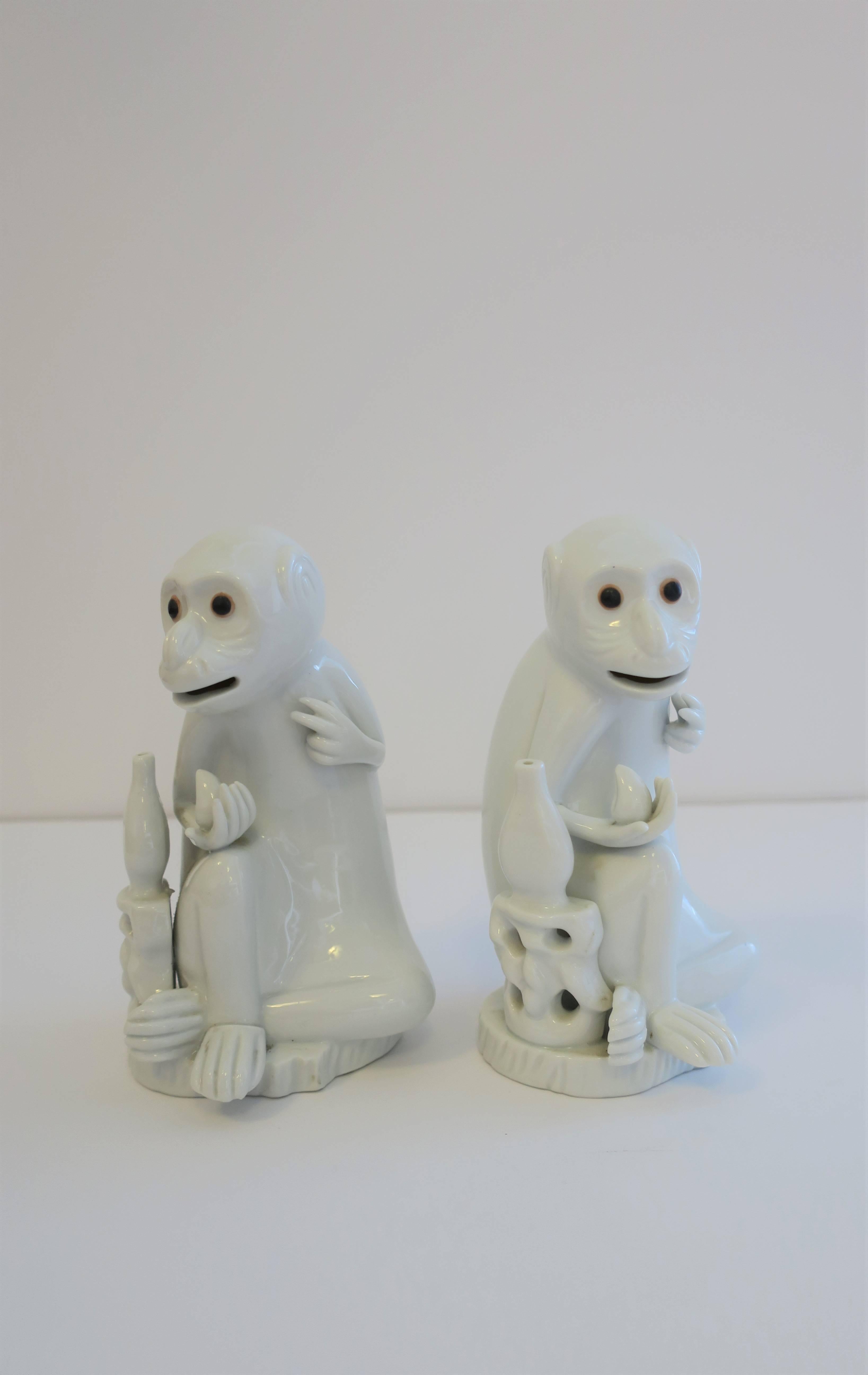 A vintage pair of detailed blanc-de-chine white porcelain monkey sculptures with dark brown eyes, in a seated position, with fruit in hand. 

Each measure: 3.63 in W x 3.50 in D x 6.50 in H.

