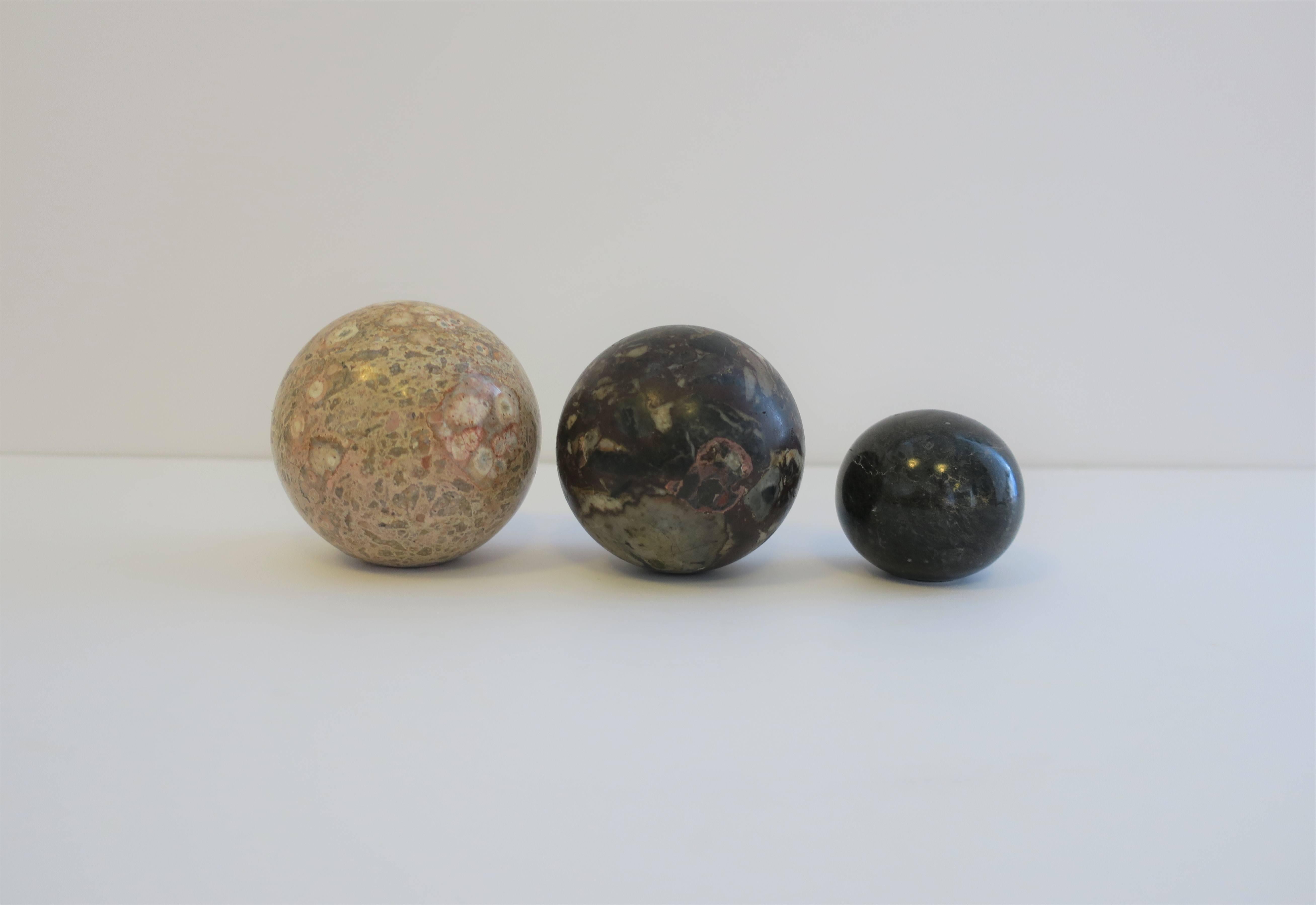 A set of three modern marble stone decorative spheres, circa 1970s. Black sphere has a 'flat' bottom 

Amongst the three sphere's, colors include: cream, sand, very light pink or flesh color, blue, green, black, dark red and traces of