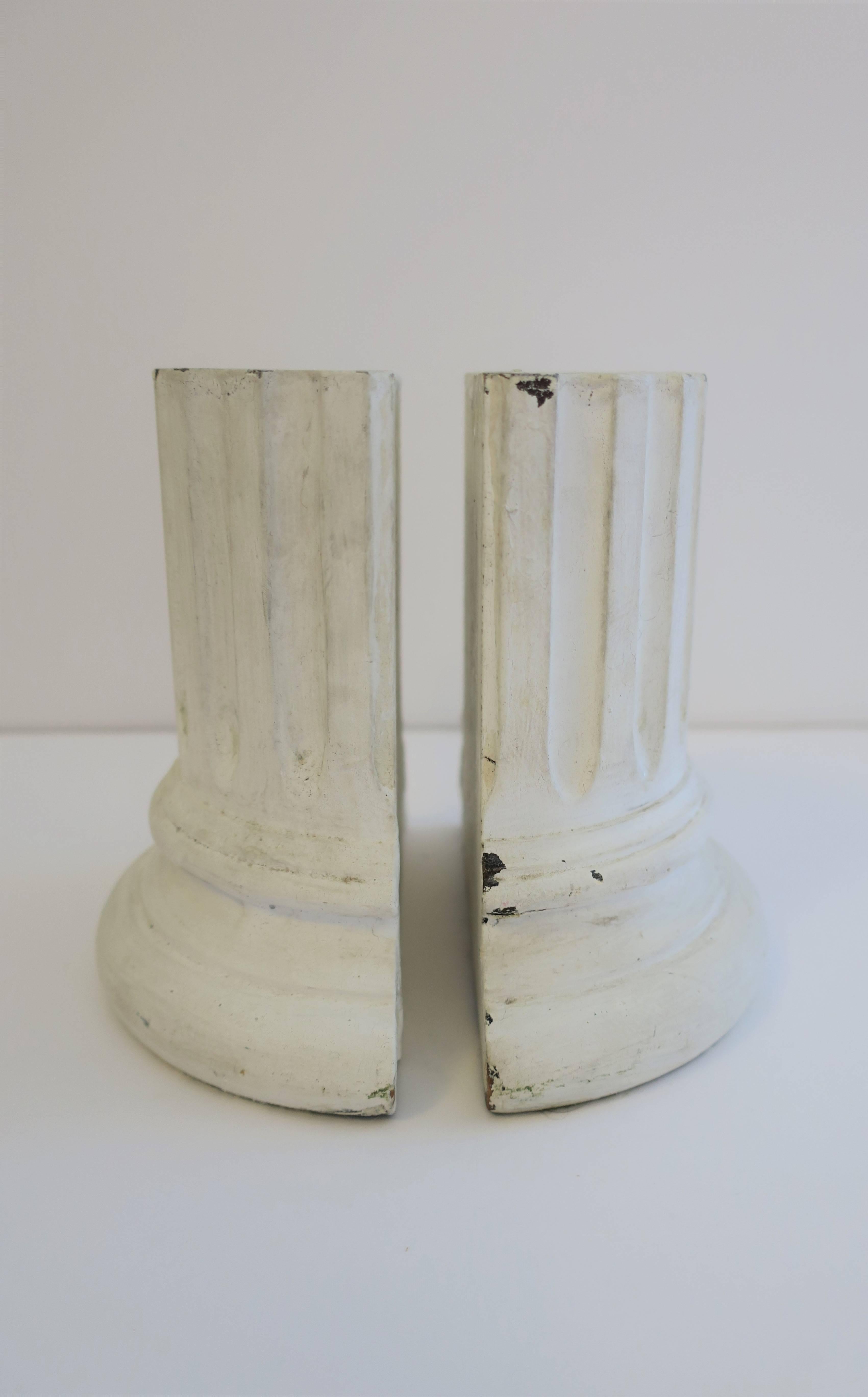 A chic pair of Midcentury or earlier white paint and plaster over wood Greek or Roman Doric style column bookends; shaft with fluting fillets and round base. 

Measurements include: 6.50