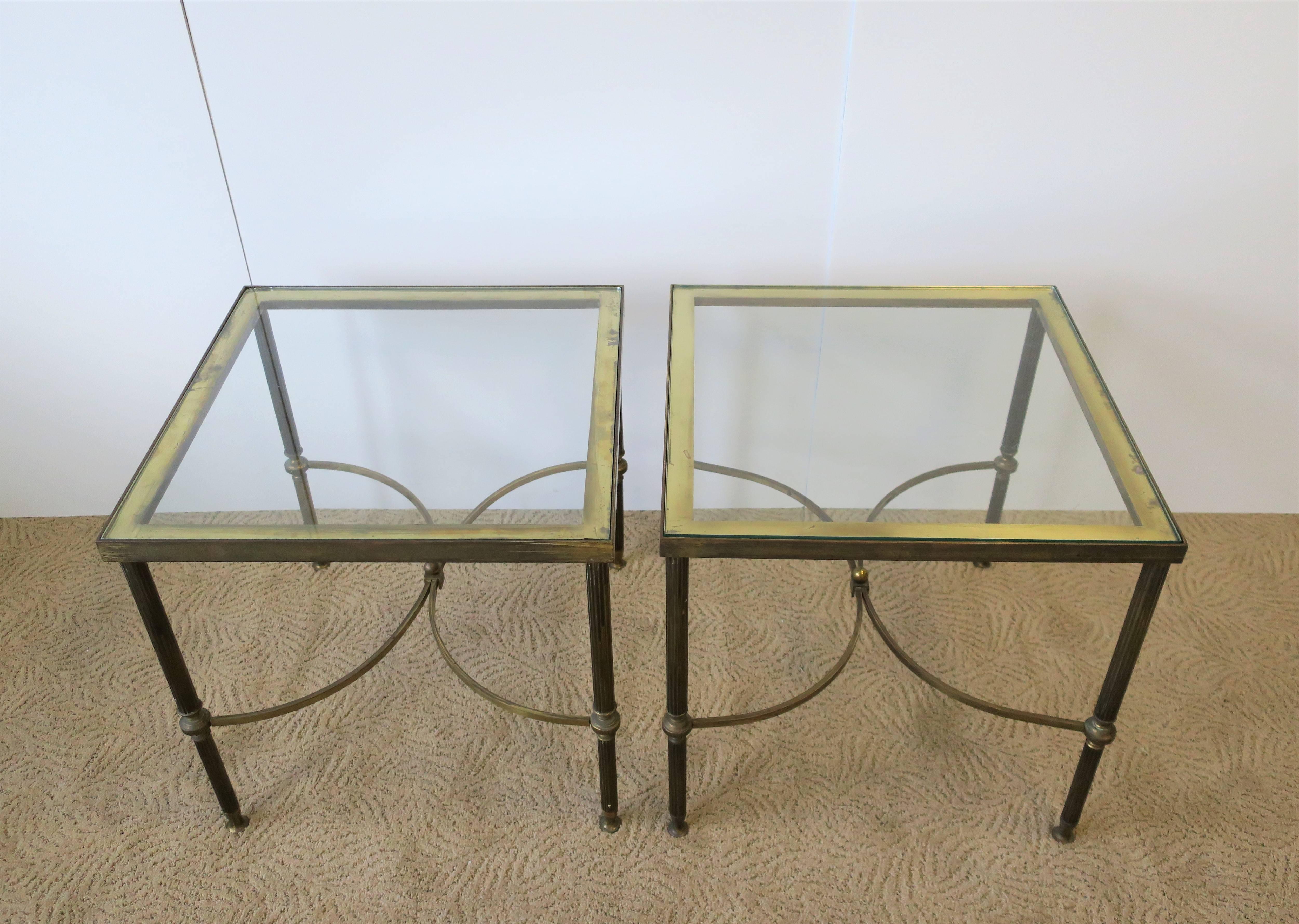 A beautiful and substantial pair of Mid-20th century European (Italian or French) square brass and glass end tables. Pair are a Directoire design style attributed to design-house Maison Jansen, circa Mid-20th Century. Brass frames have decorative