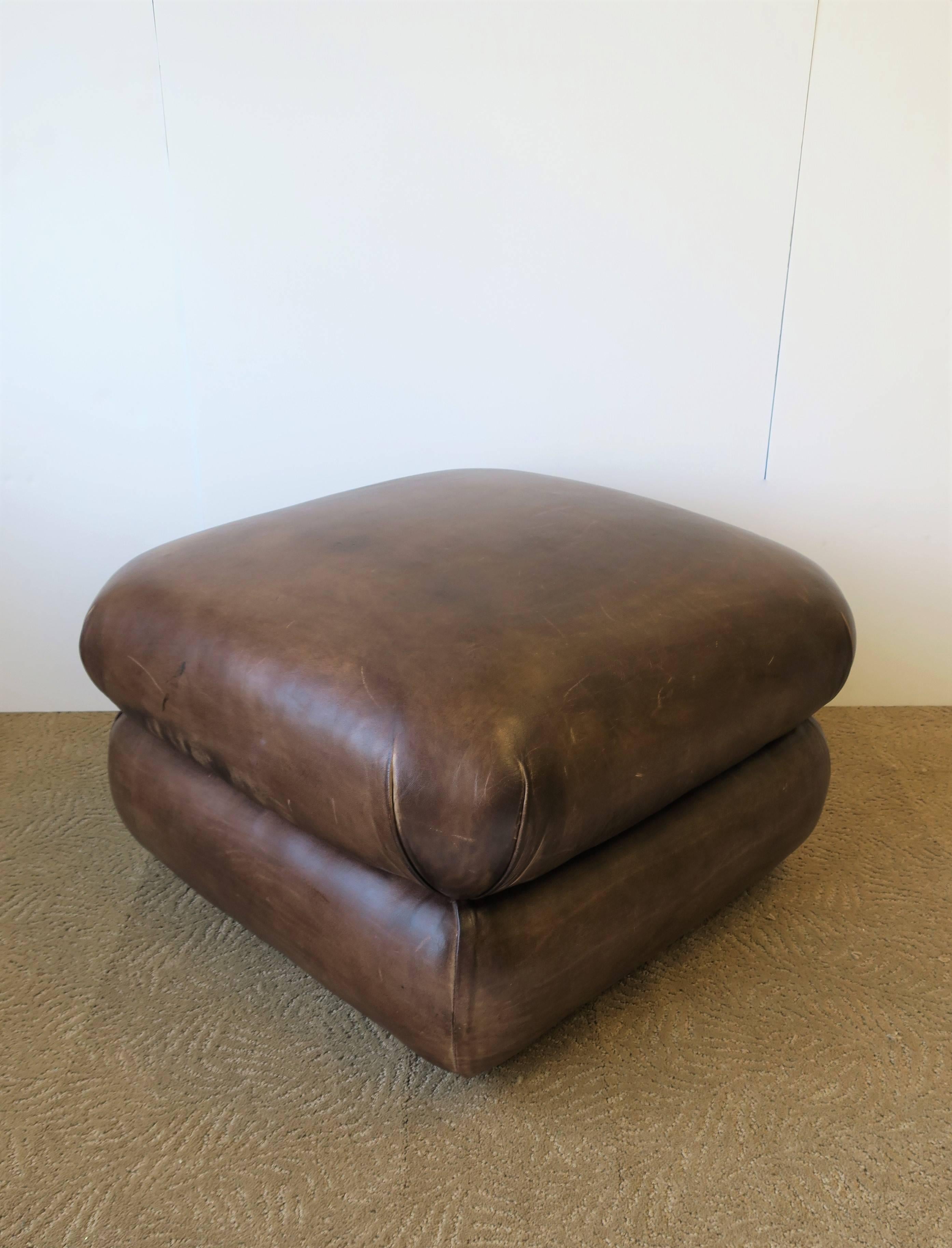 A Postmodern or Modern style brown leather ottoman by George Smith, England, circa 1990s. Ottoman is professionally upholstered by George Smith Ltd., in a beautiful brown leather supported by four hidden caster wheels. Ottoman is firm and